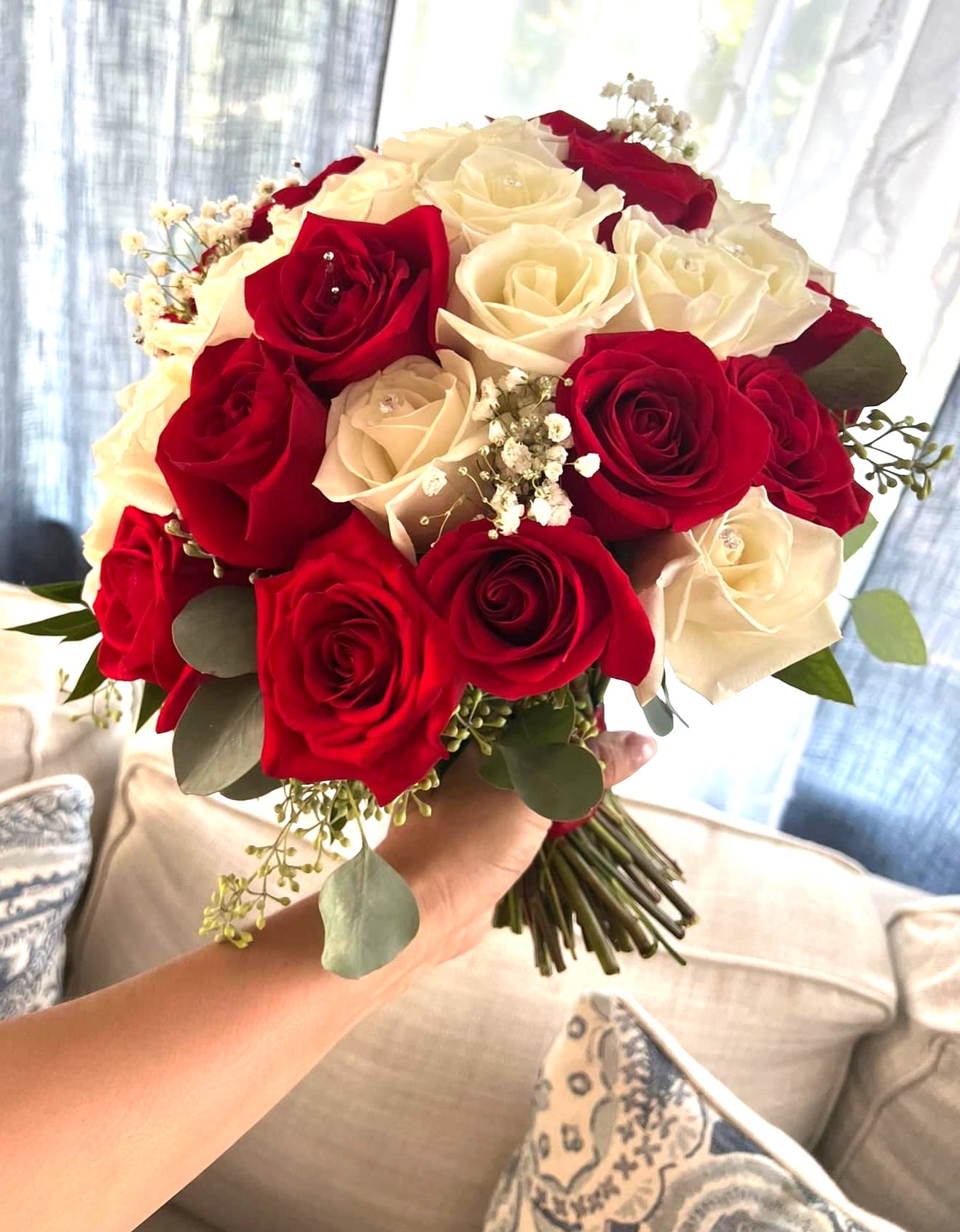 Handheld bouquet of red and white roses with small white filler flowers