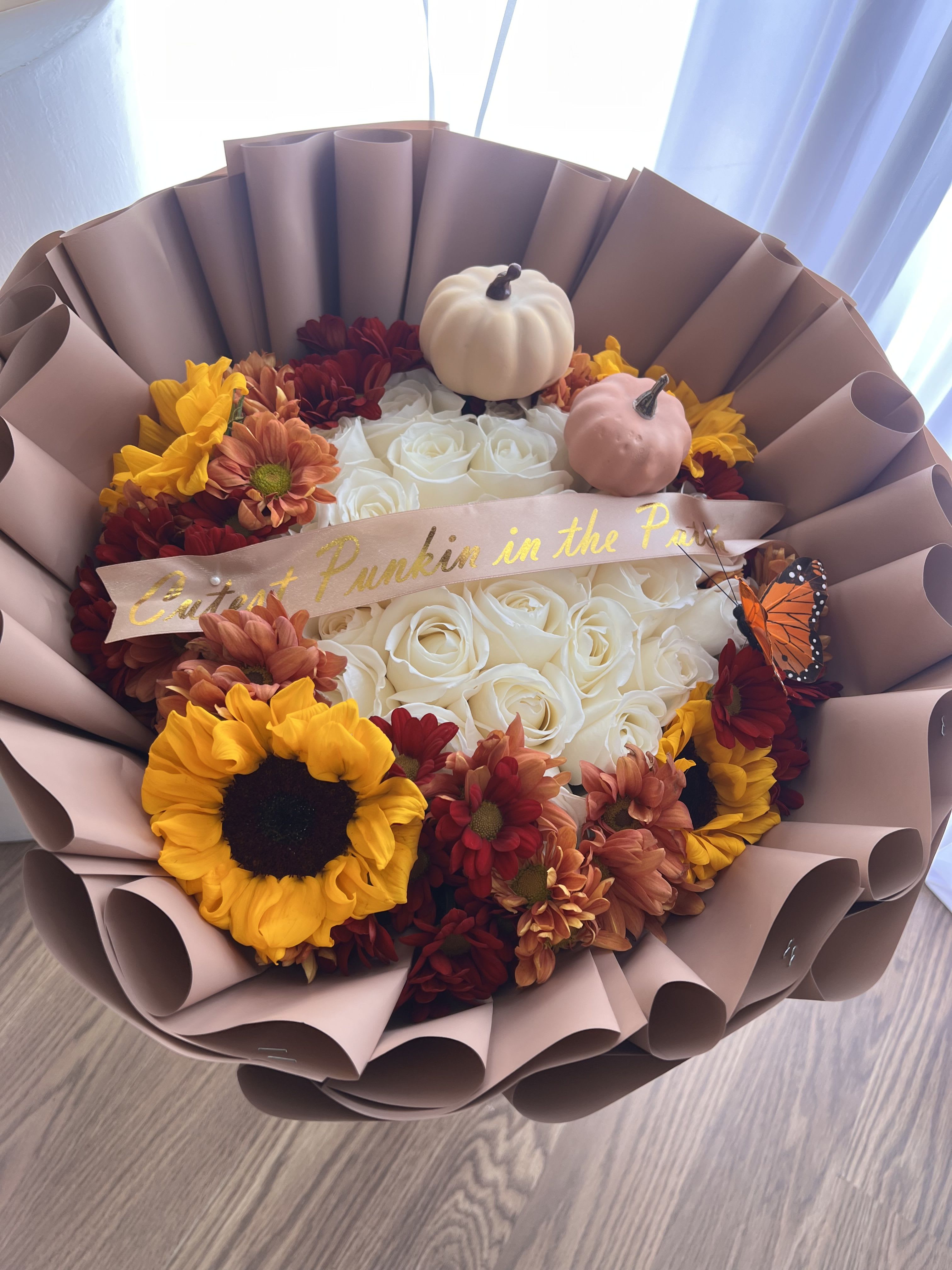 Bouquet of white roses with sunflowers and small pumpkins