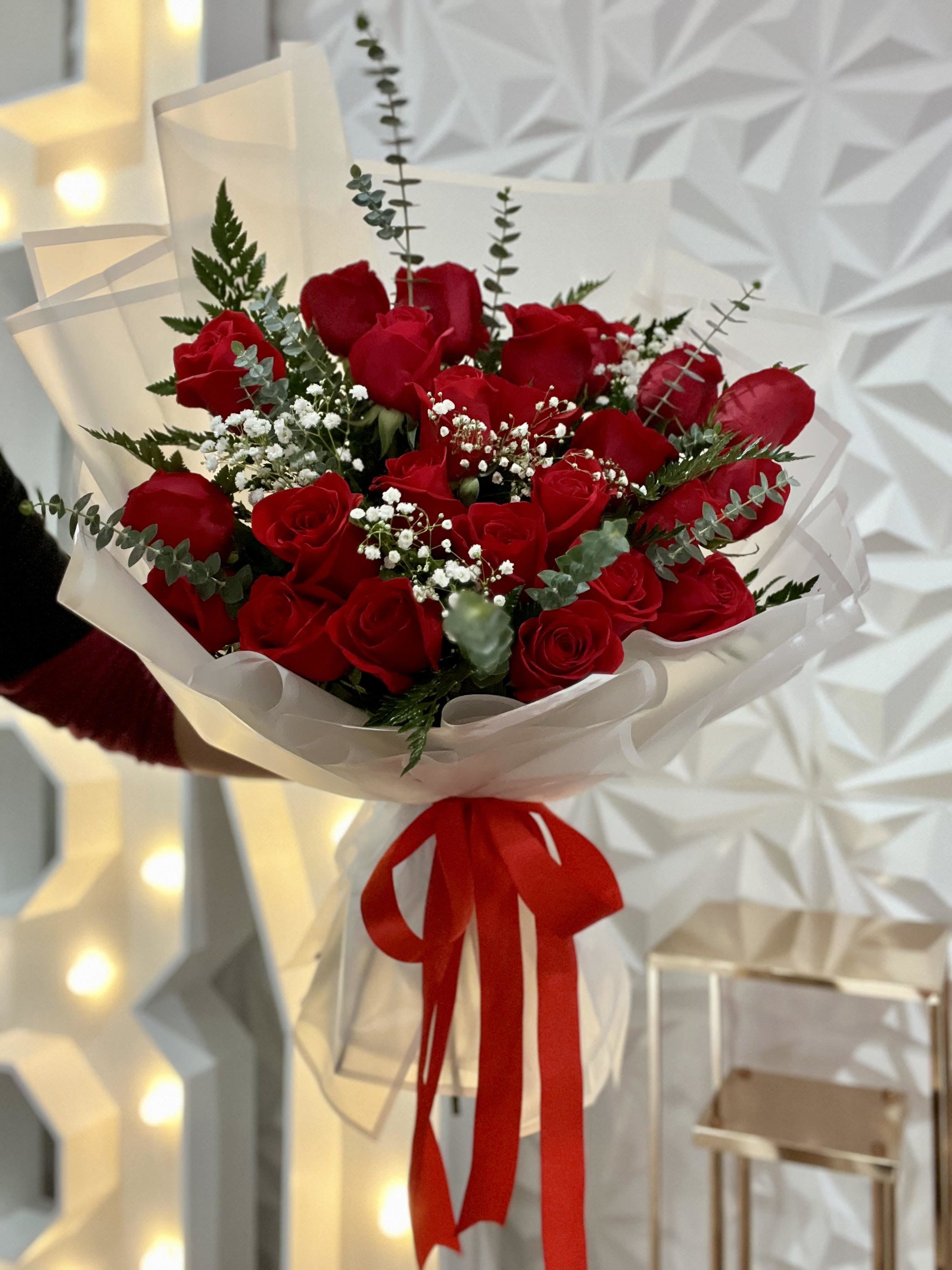 Bouquet of red roses wrapped in white paper with a red ribbon