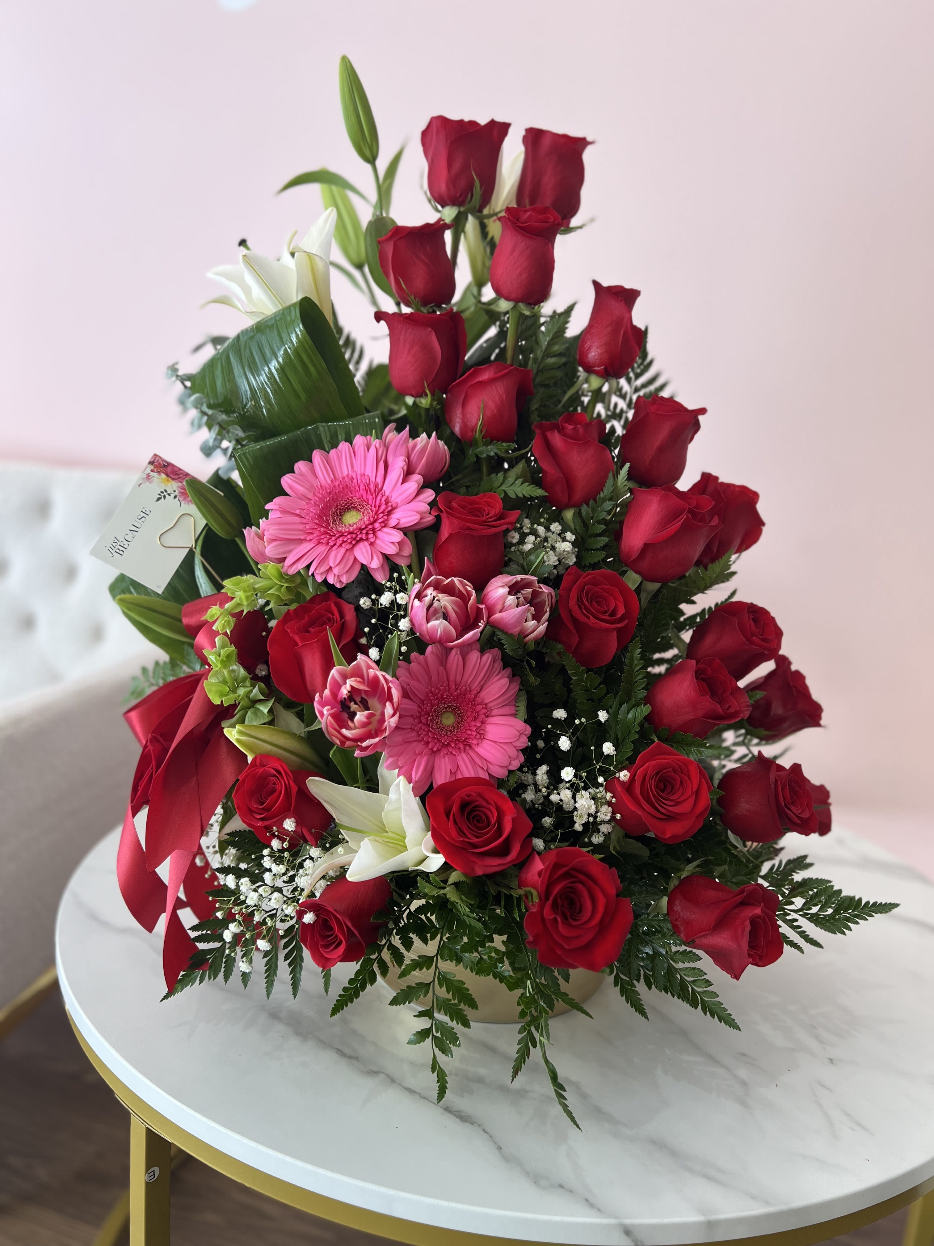 Bouquet of red roses, pink gerberas, and white lilies with a red ribbon
