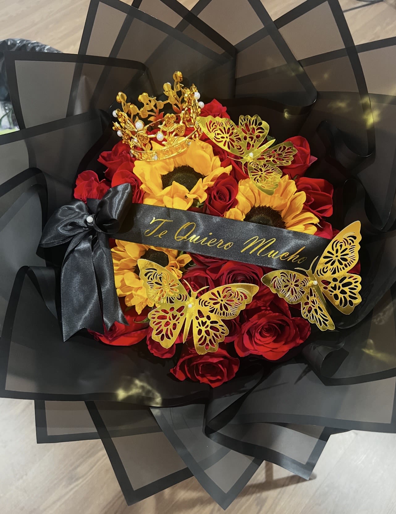 Bouquet of red roses and sunflowers with black wrapping and gold butterfly accents