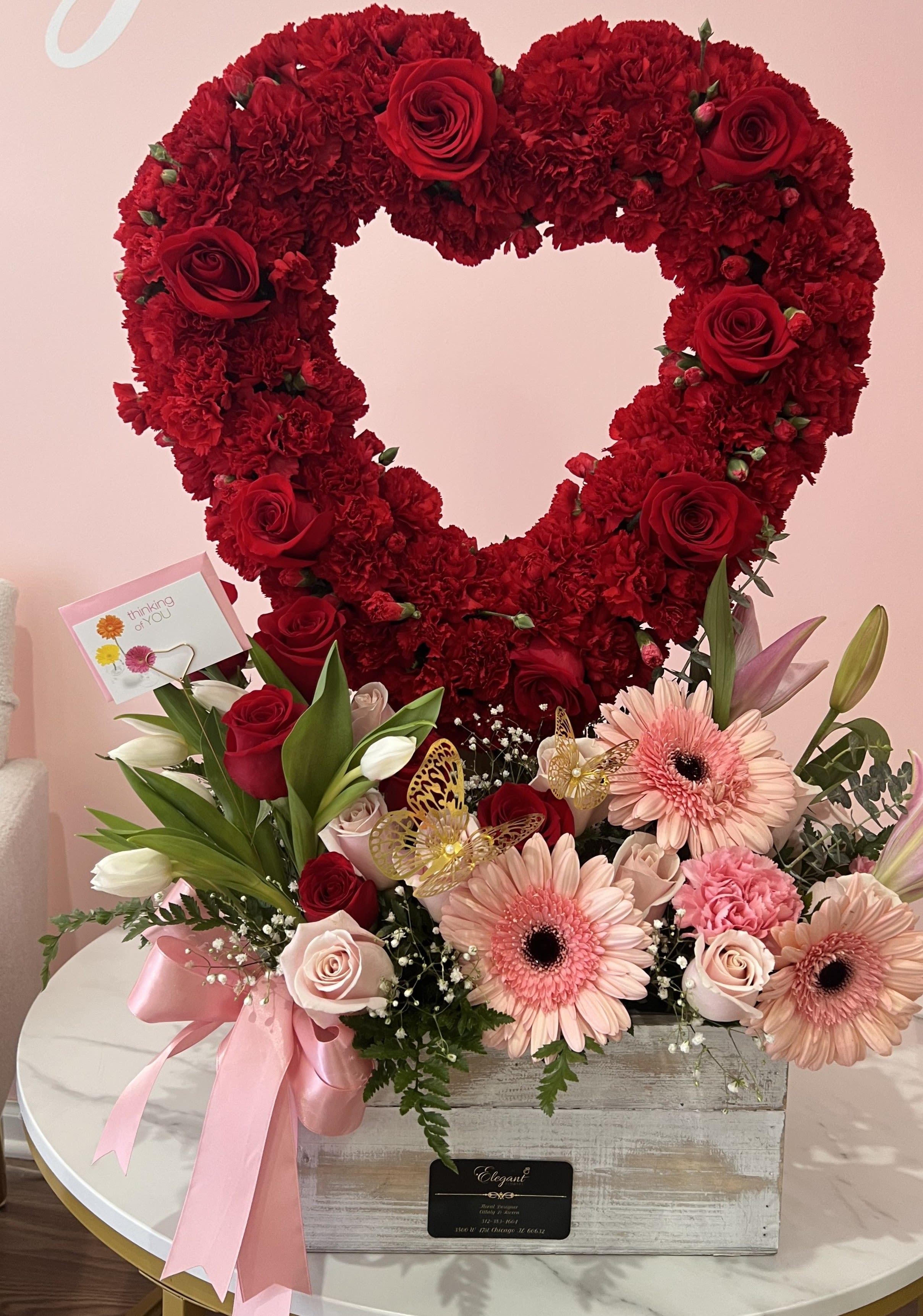 Heart-shaped red flower arrangement with pink blooms in a wooden box