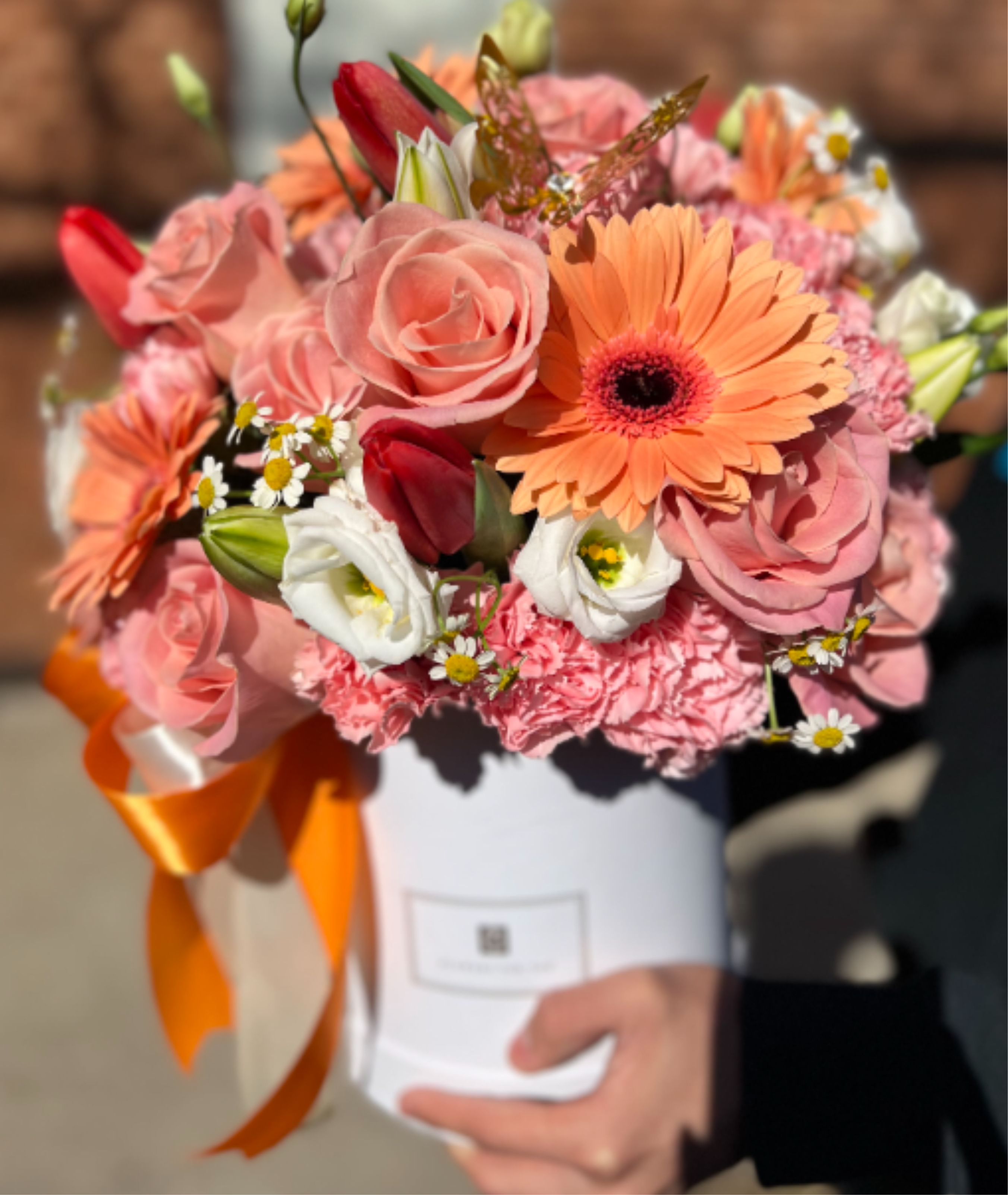 Blossom Luxe Collection - A spring-style floral box arrangement featuring the delicacy of peach roses, vibrant gerberas, soft pink carnations, and elegant tulips. It is complemented with fresh touches of chamomile and the sophistication of lilies, creating a harmonious, cheerful, and lively composition. Perfect for expressing happiness, affection, and a colorful, fresh gift.  