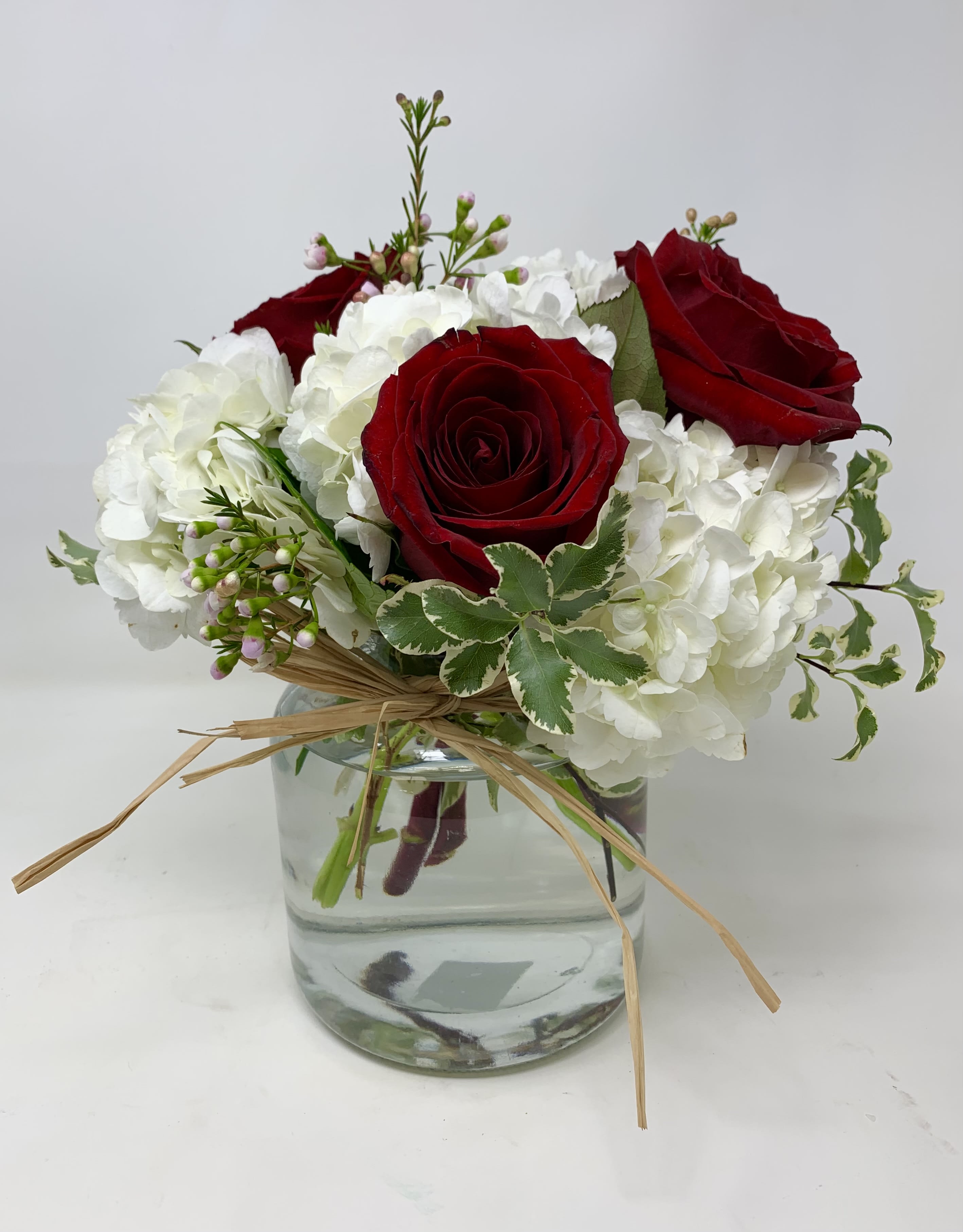 Petite Elegance - Floral arrangement consisting of red roses, hydrangeas and foliage.   *NOTE: Roses can be changed to a different traditional color upon request*