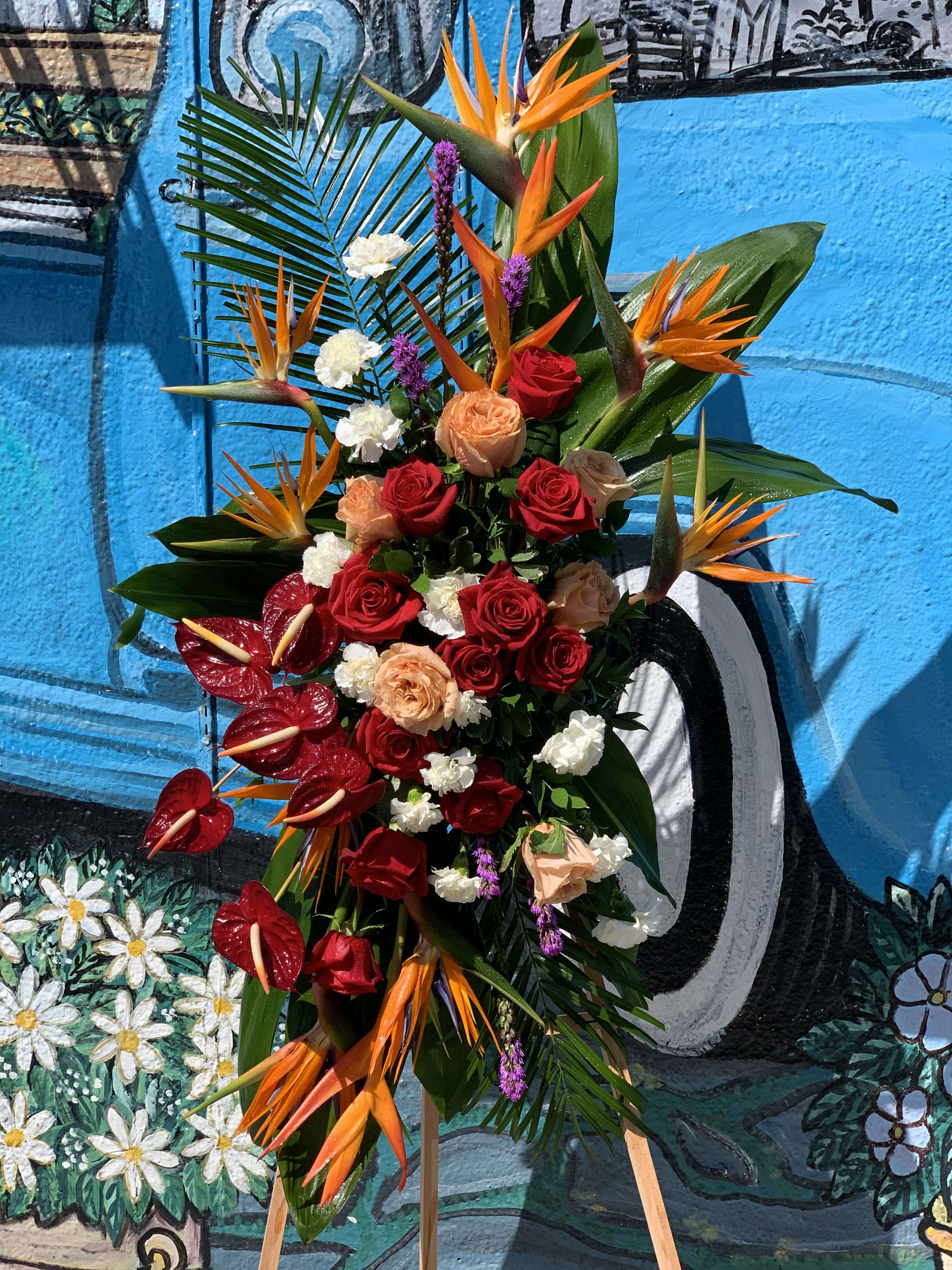 Tropical floral arrangement with red roses and orange bird-of-paradise flowers