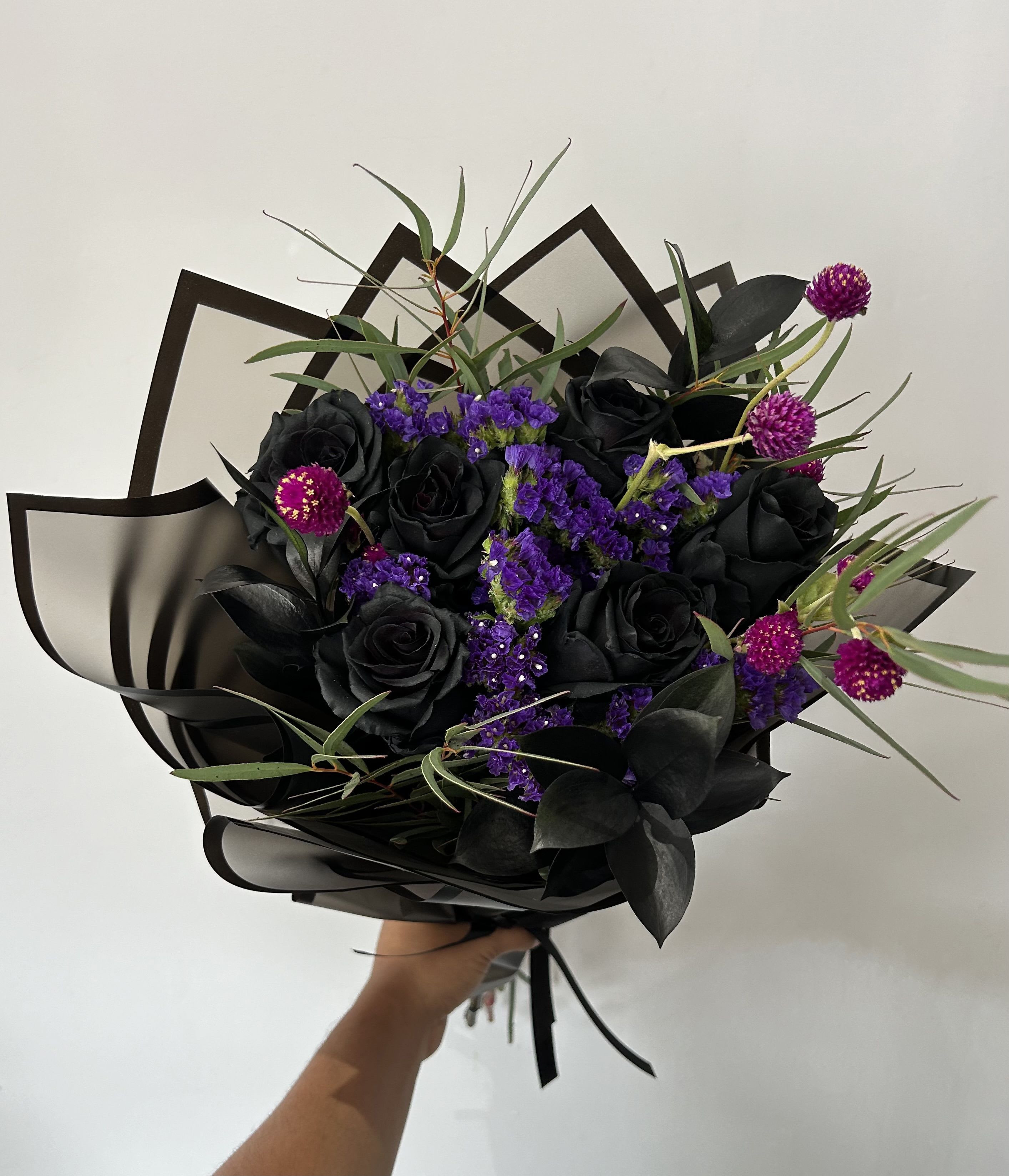 Black rose bouquet with purple filler flowers and dark foliage