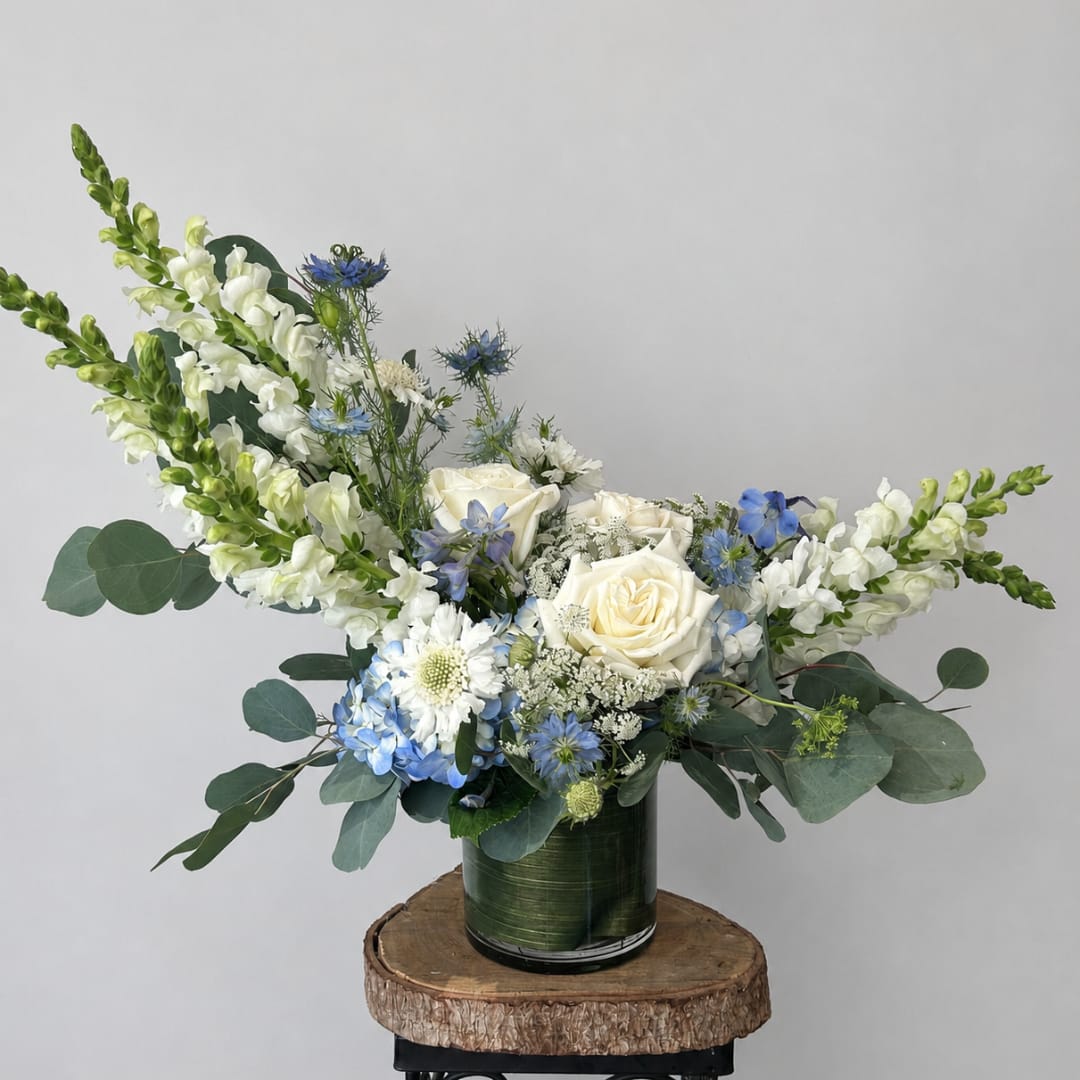 White roses and blue flowers in a green vase
