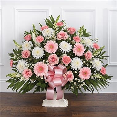 Pink and white floral arrangement in a white vase with a pink ribbon