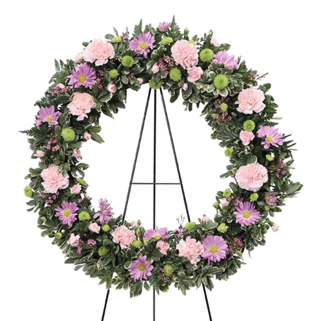 Standing circular wreath with pink carnations and lavender daisies on a metal easel