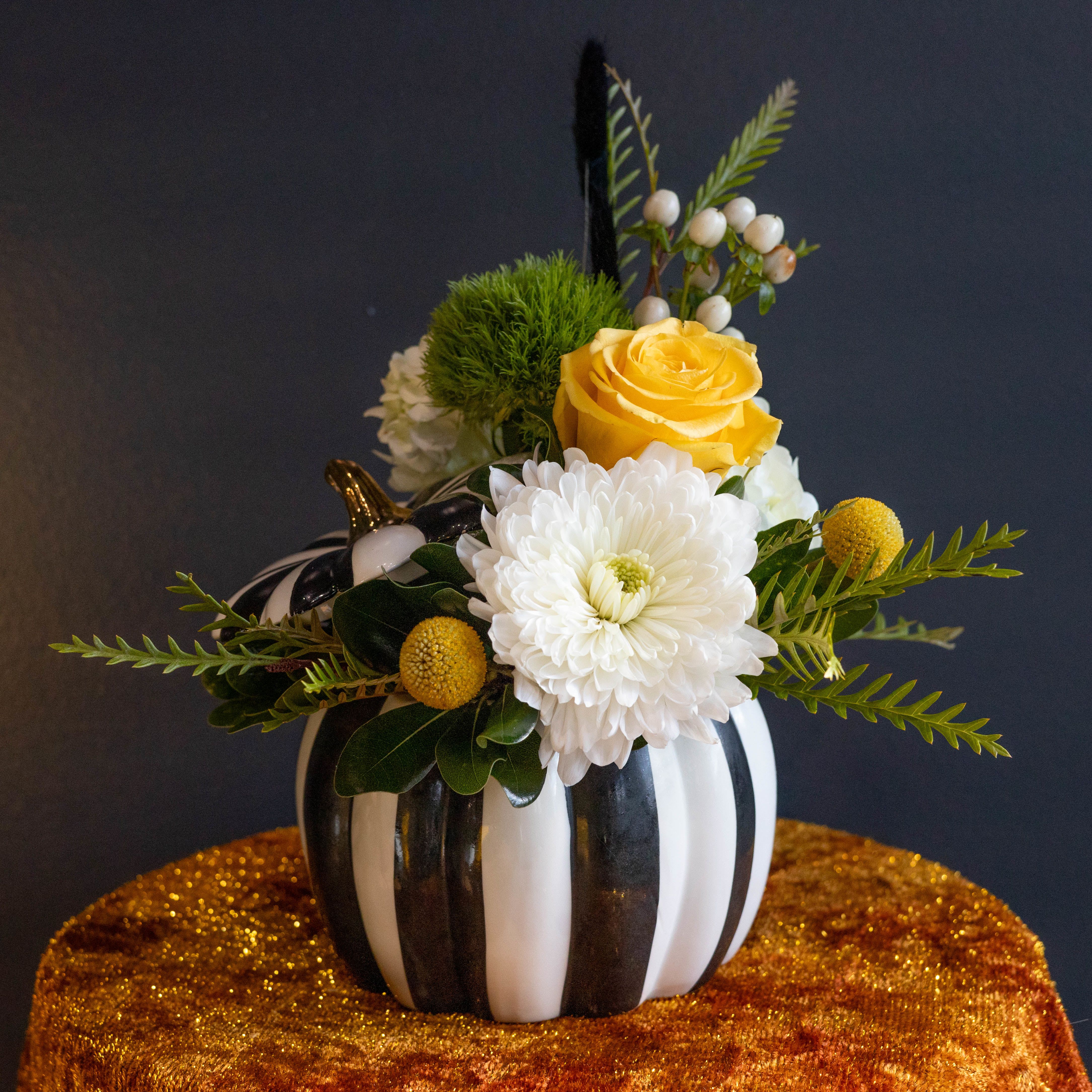 Yellow rose and white chrysanthemum arrangement in a striped pumpkin vase