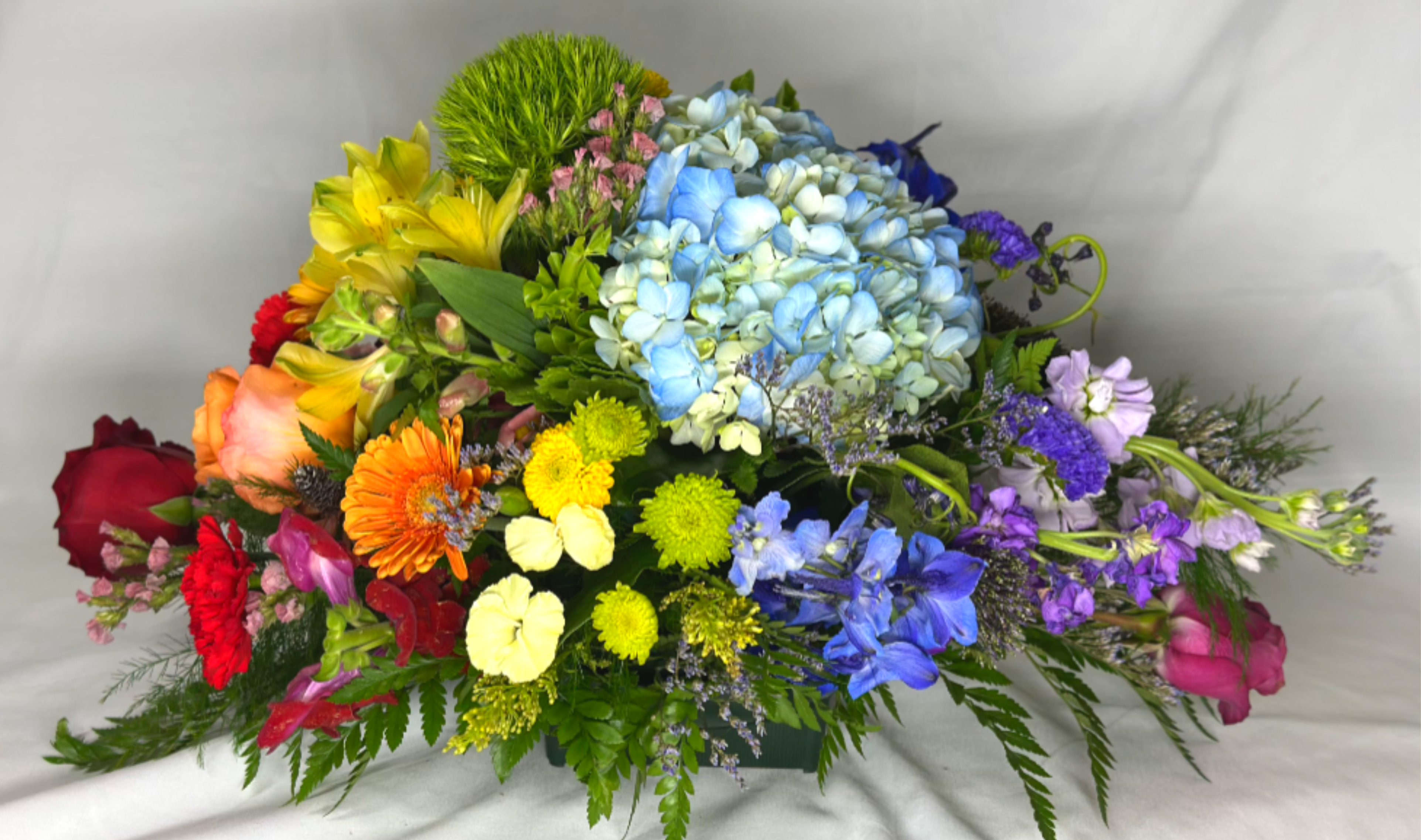 Over the Rainbow  - We love chasing rainbows. This Leary's flowers exclusive design features red, orange, yellow, green, blue, indigo, and violet blossoms arrangement just like the colors of the rainbow. It will be a cheerful Mother's Day bouquet, or an expression of sympathy, or just to make someone smile. The blossoms in this colorful design will vary by season ensuring the highest quality flowers for your gift. 