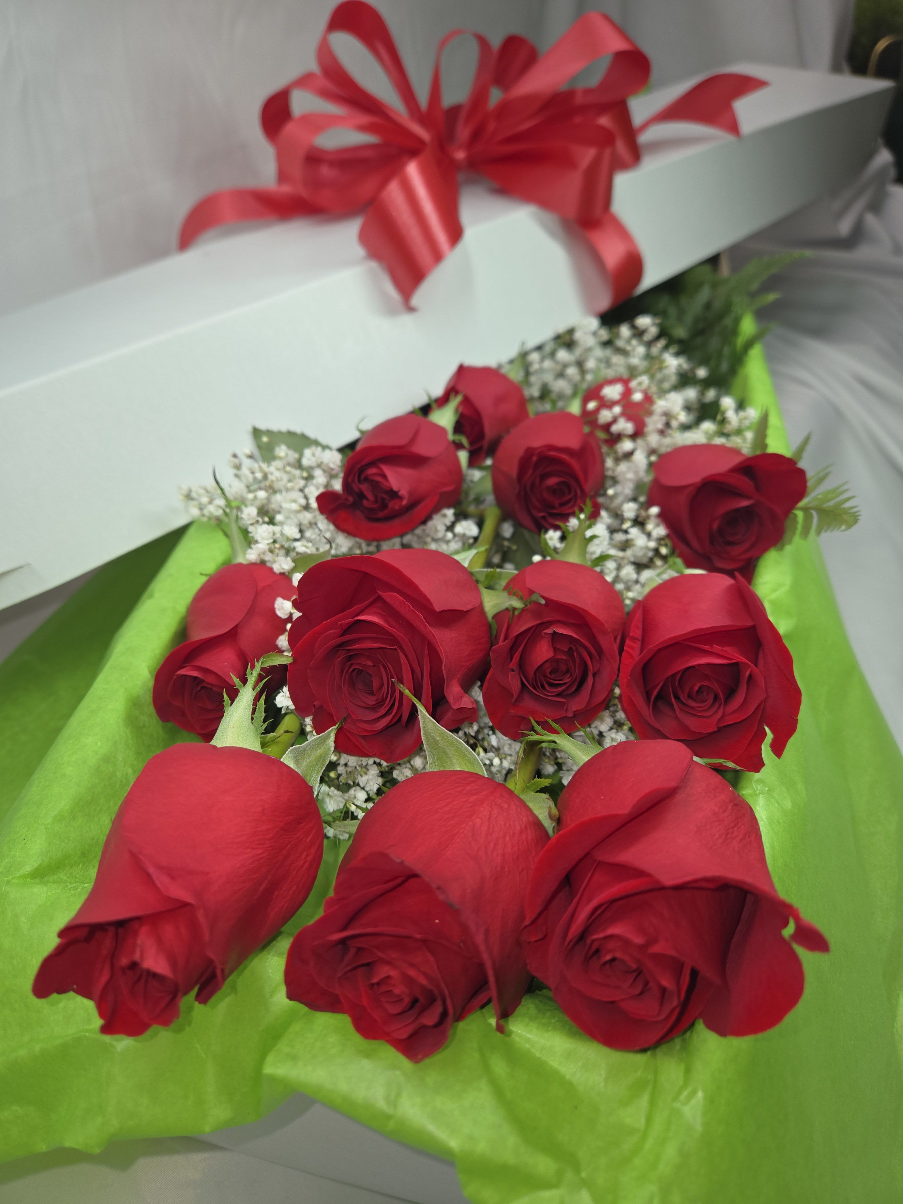 Box of red roses with baby's breath and a red ribbon bow