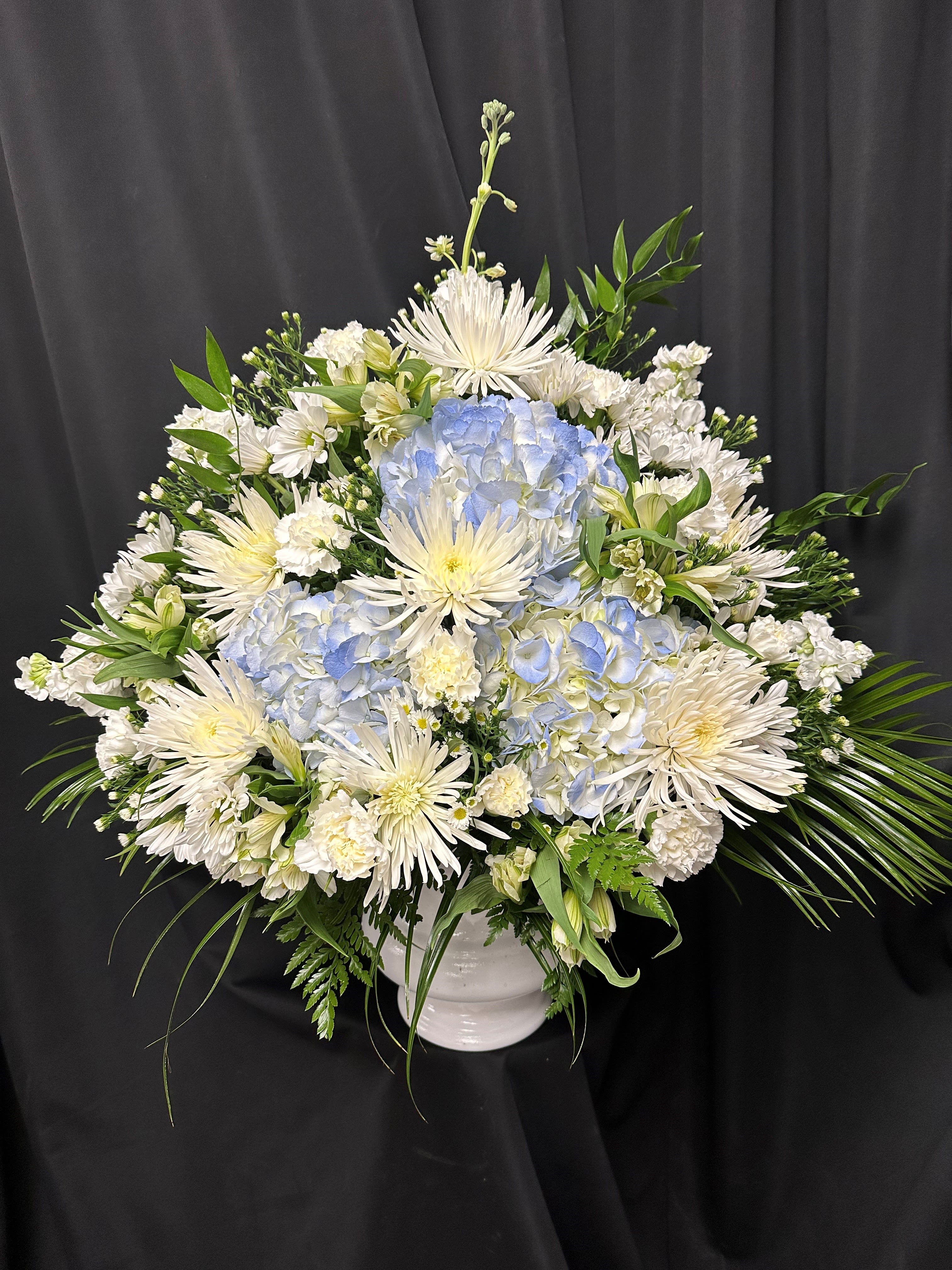White and pale blue floral arrangement in a white vase