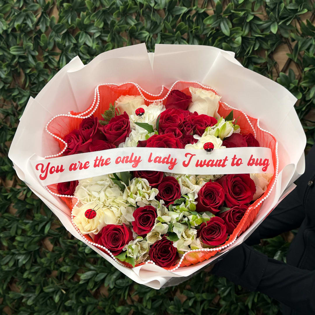 Bouquet of red and white roses wrapped in white paper with a ribbon