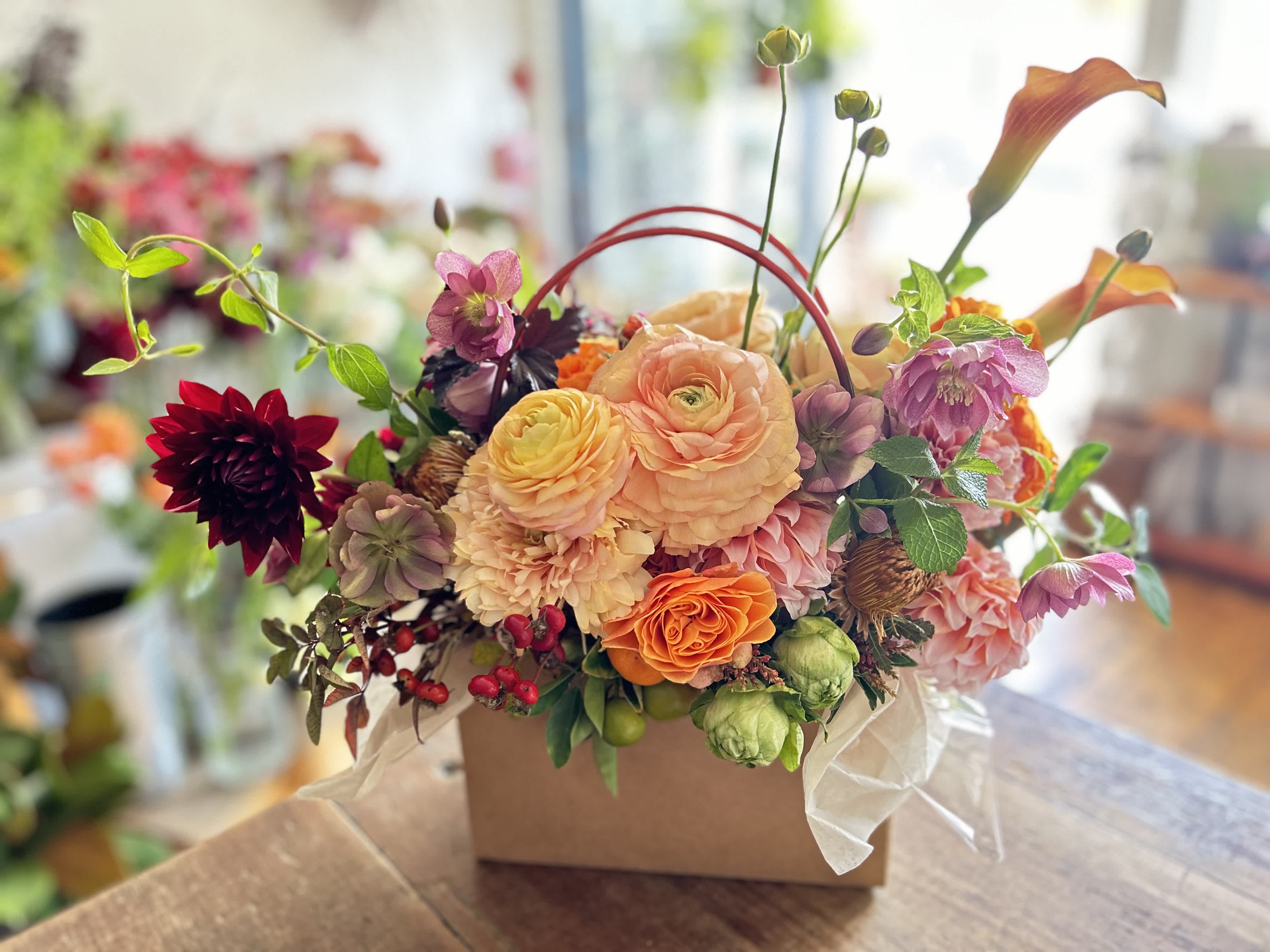 Mixed floral arrangement in a square box with peach, pink, orange, and burgundy blooms