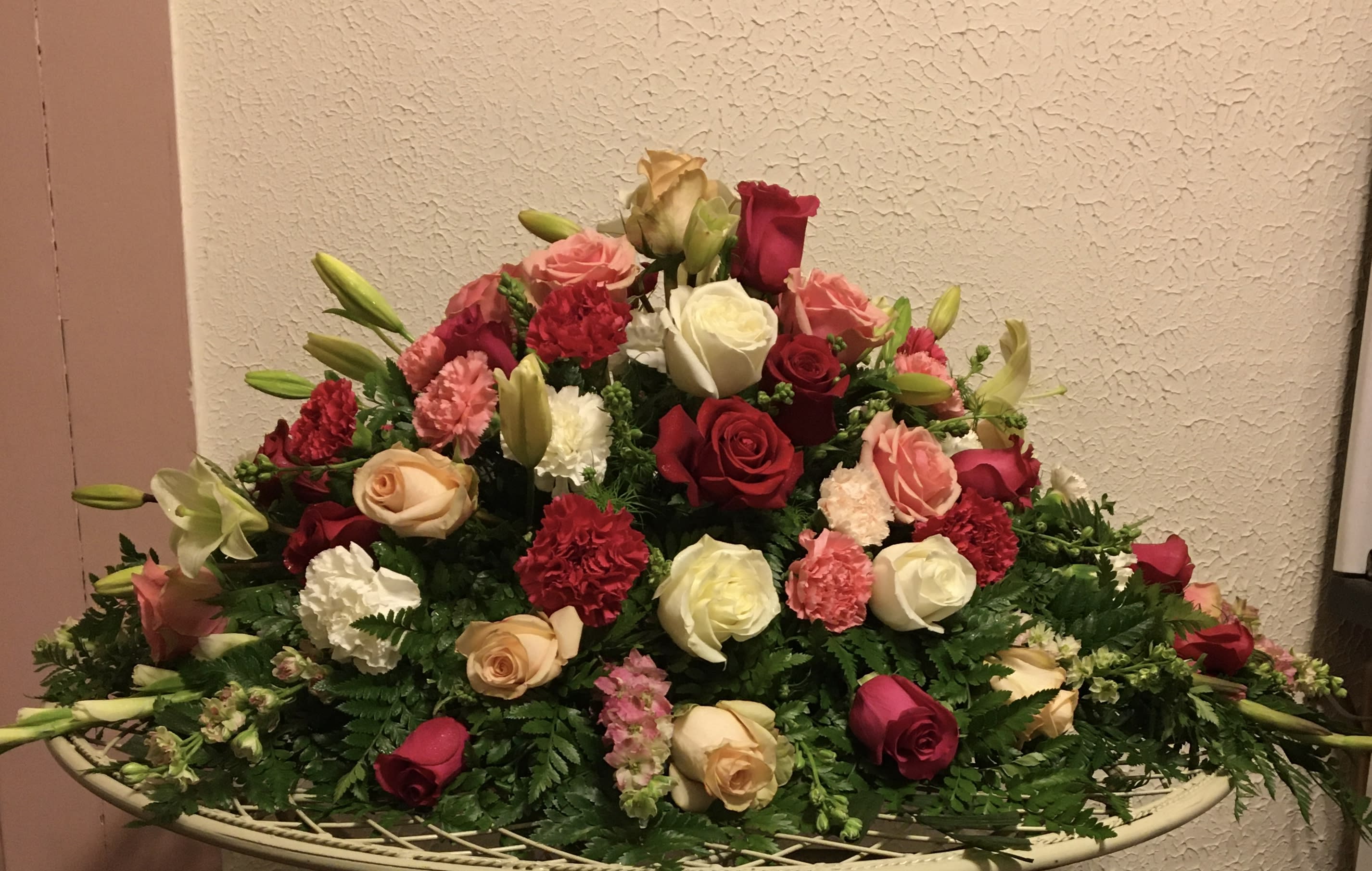 Large mixed bouquet of roses, lilies, and carnations in a low basket