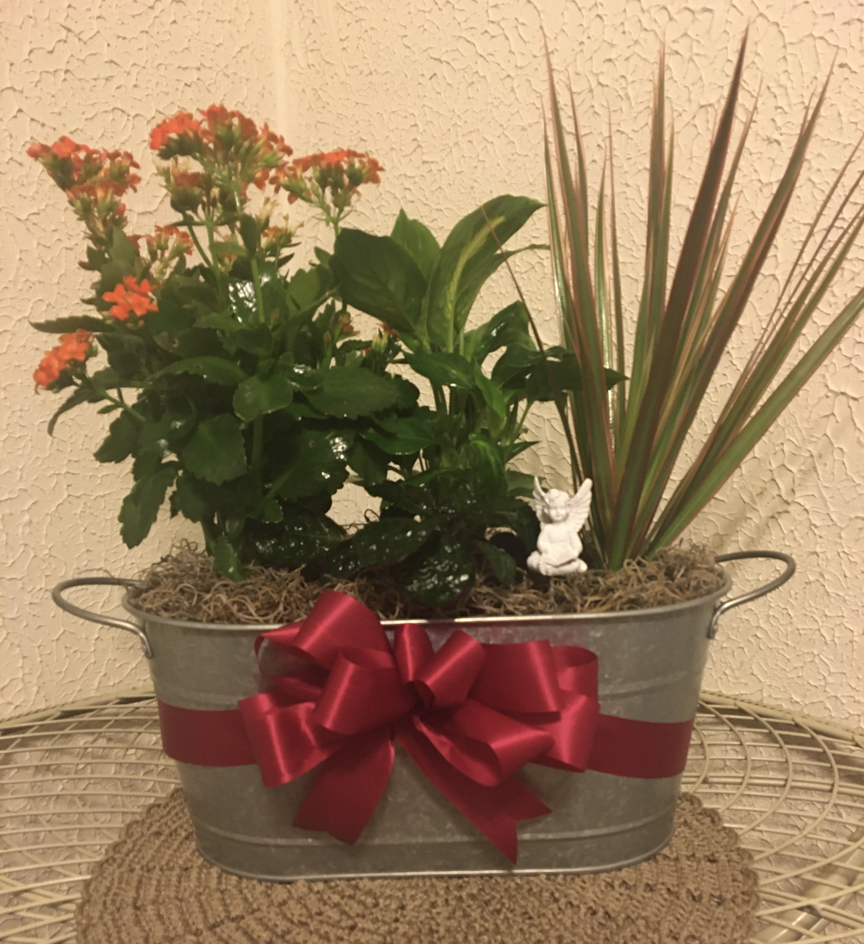 Potted flowering plant arrangement in a metal tub with a red ribbon