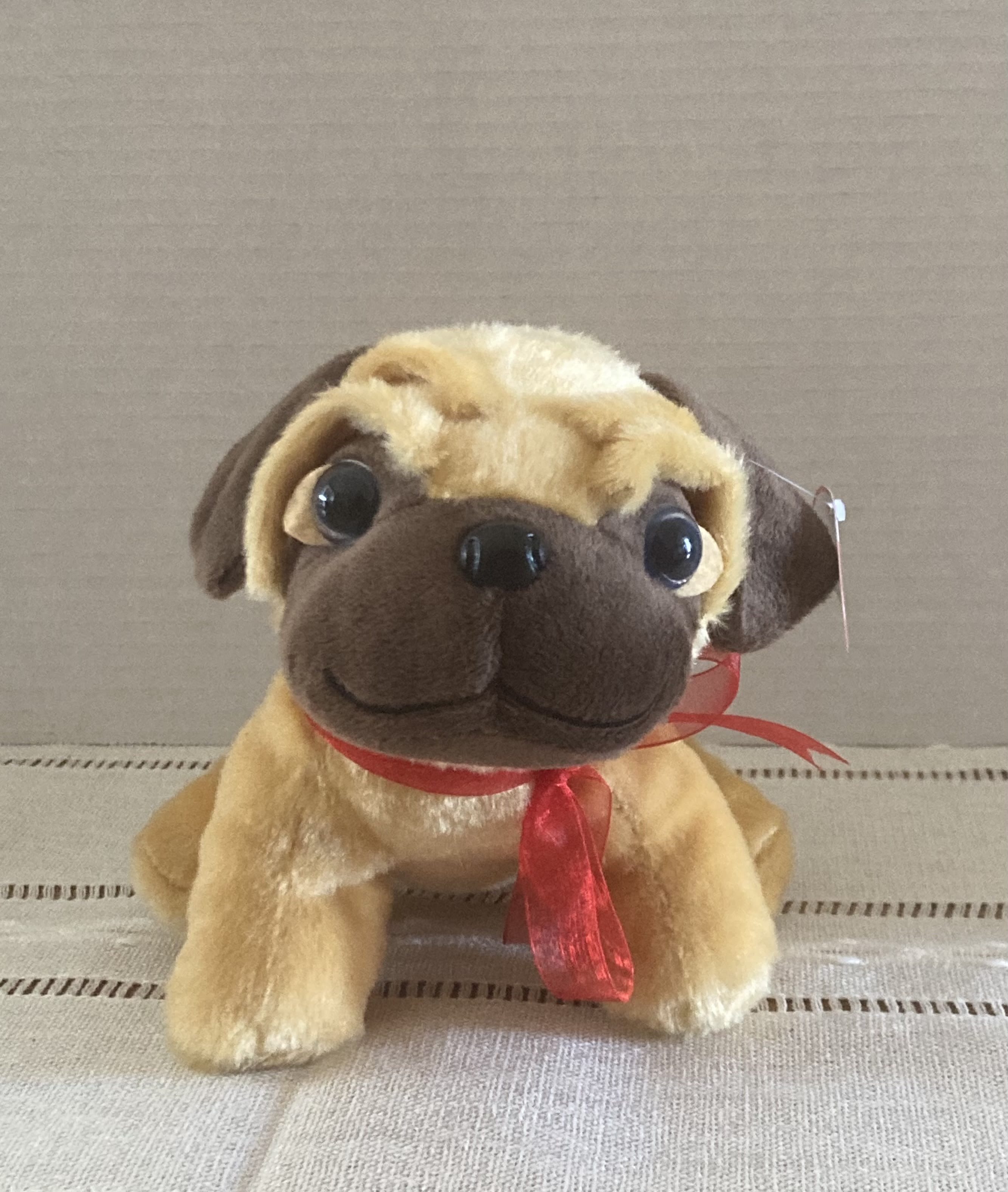 Plush pug toy with a red ribbon around its neck