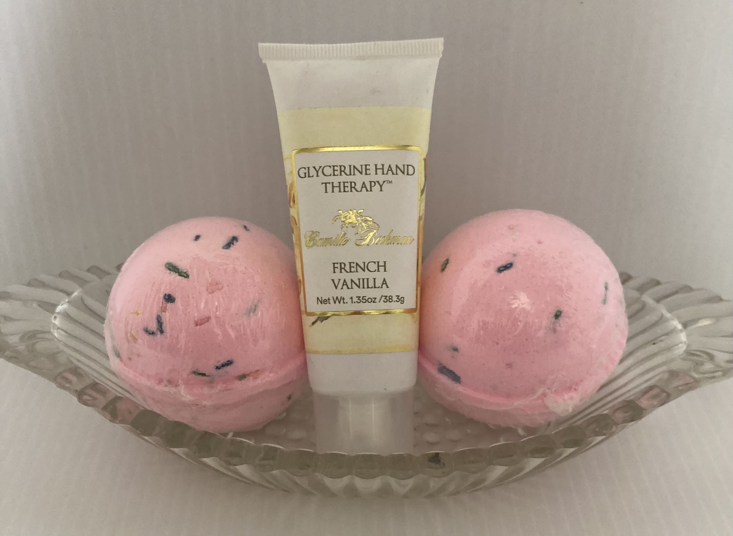 Hand therapy tube in a glass dish with two pink bath bombs