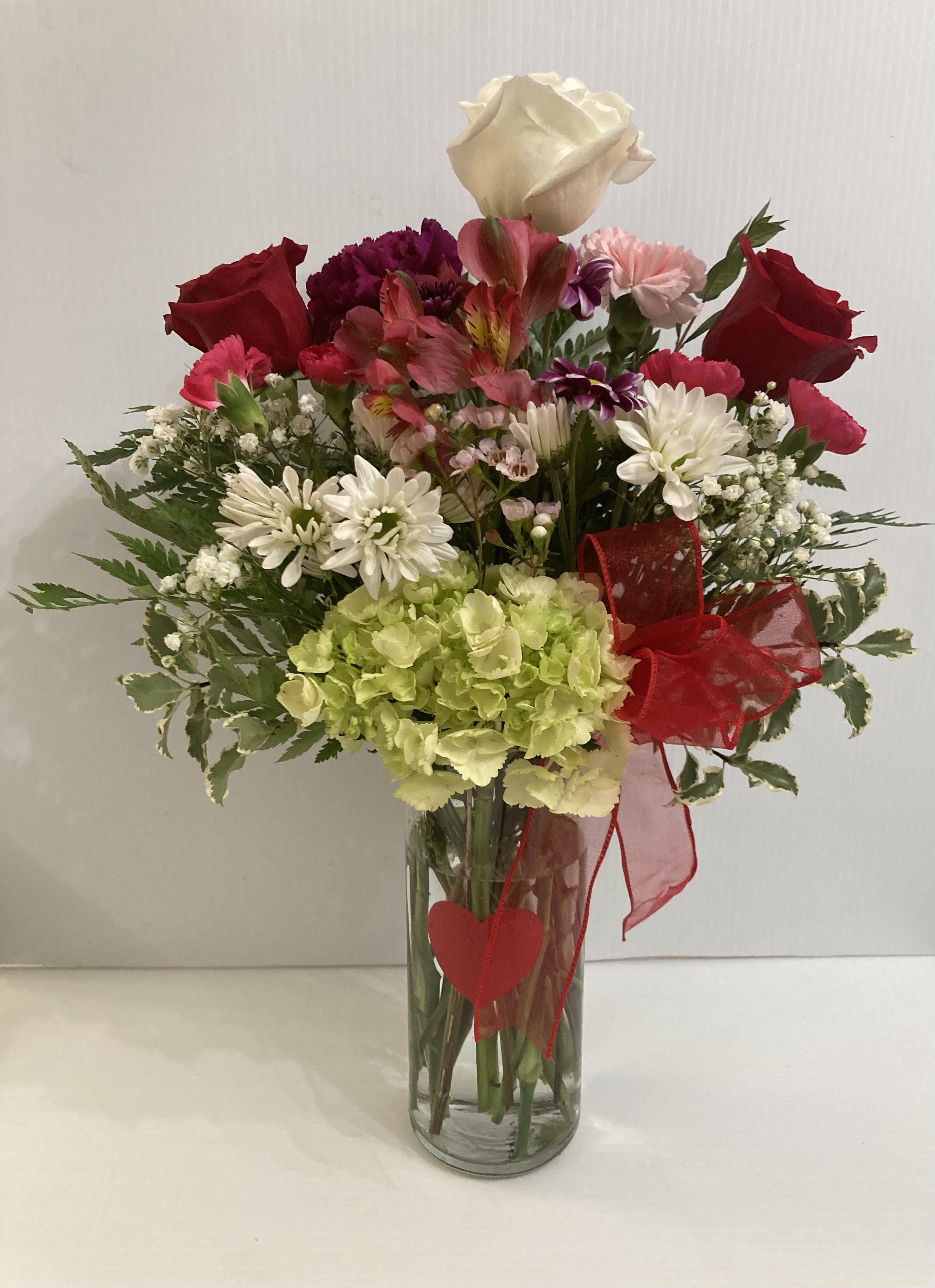 Mixed bouquet in a clear glass vase with red roses and white daisies