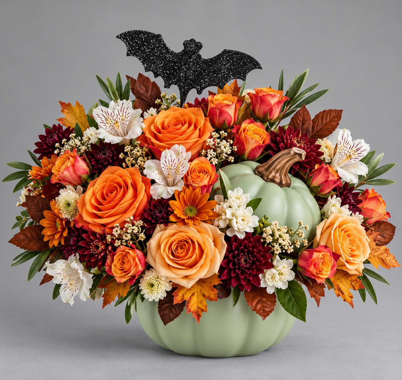 Autumn floral arrangement in a pumpkin vase with a bat topper