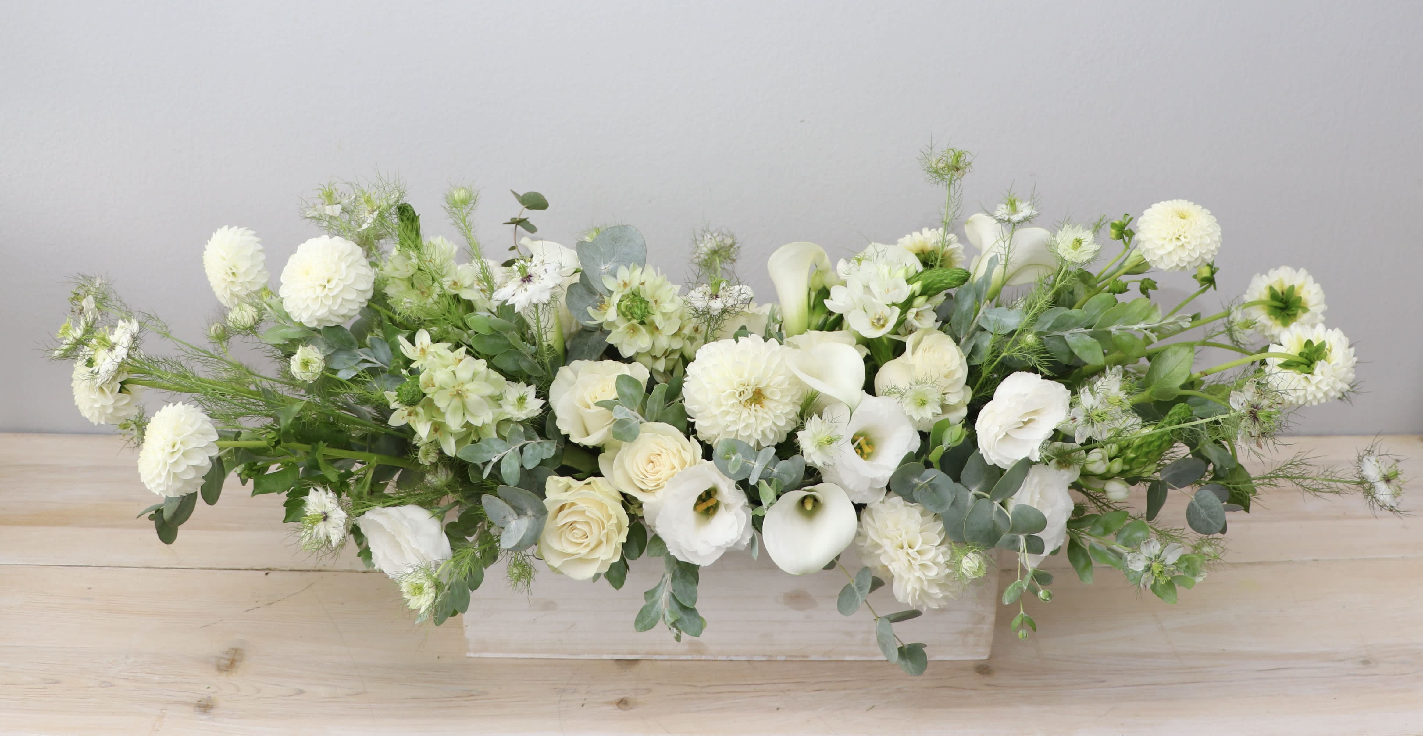 Long white floral arrangement in a low rectangular container