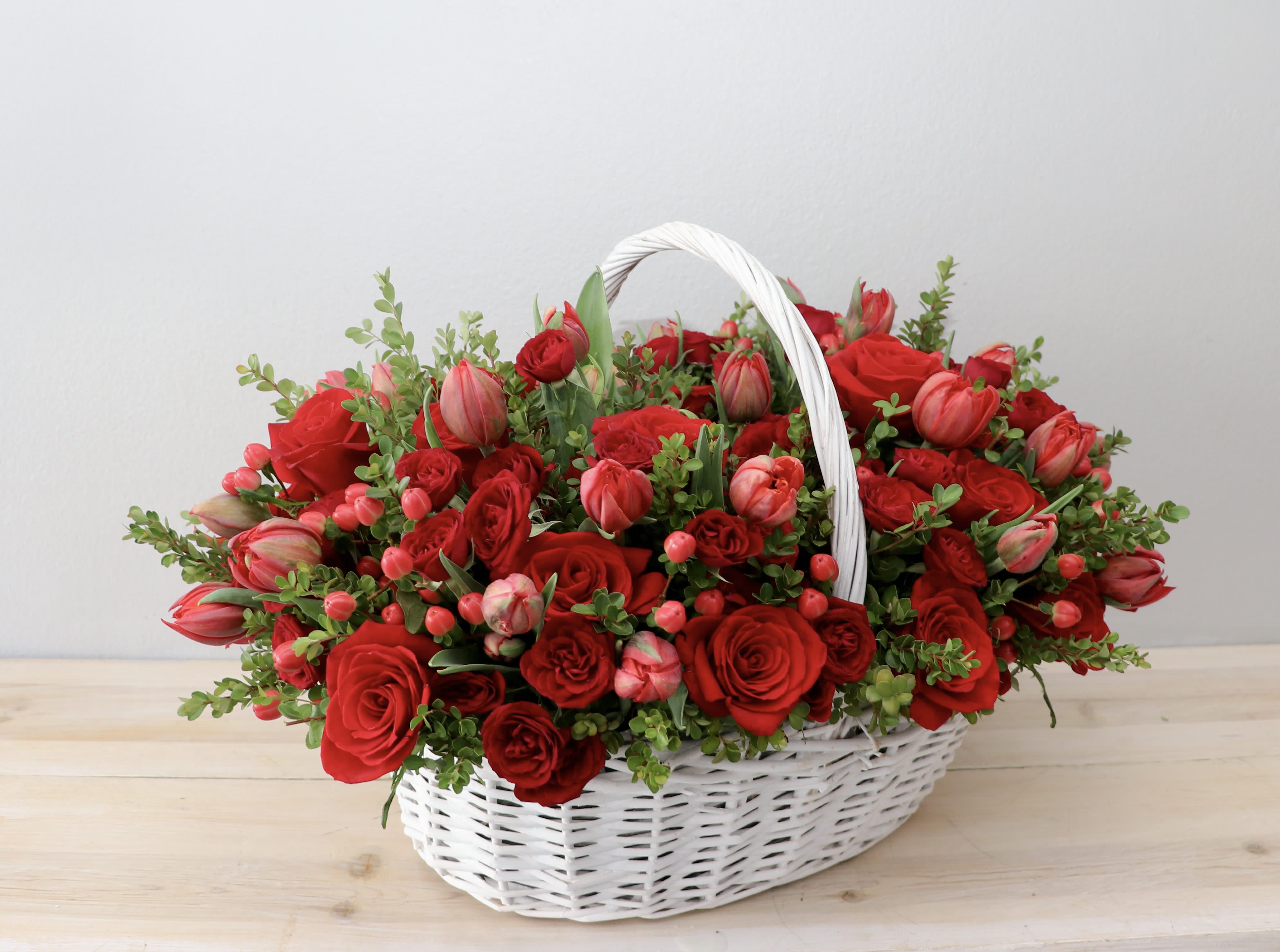 Basket of red roses and pink tulips with greenery