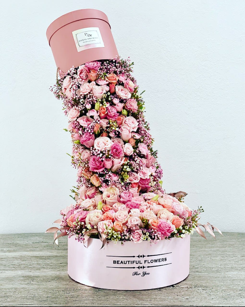 Tall pink hatbox arrangement of roses and baby’s breath