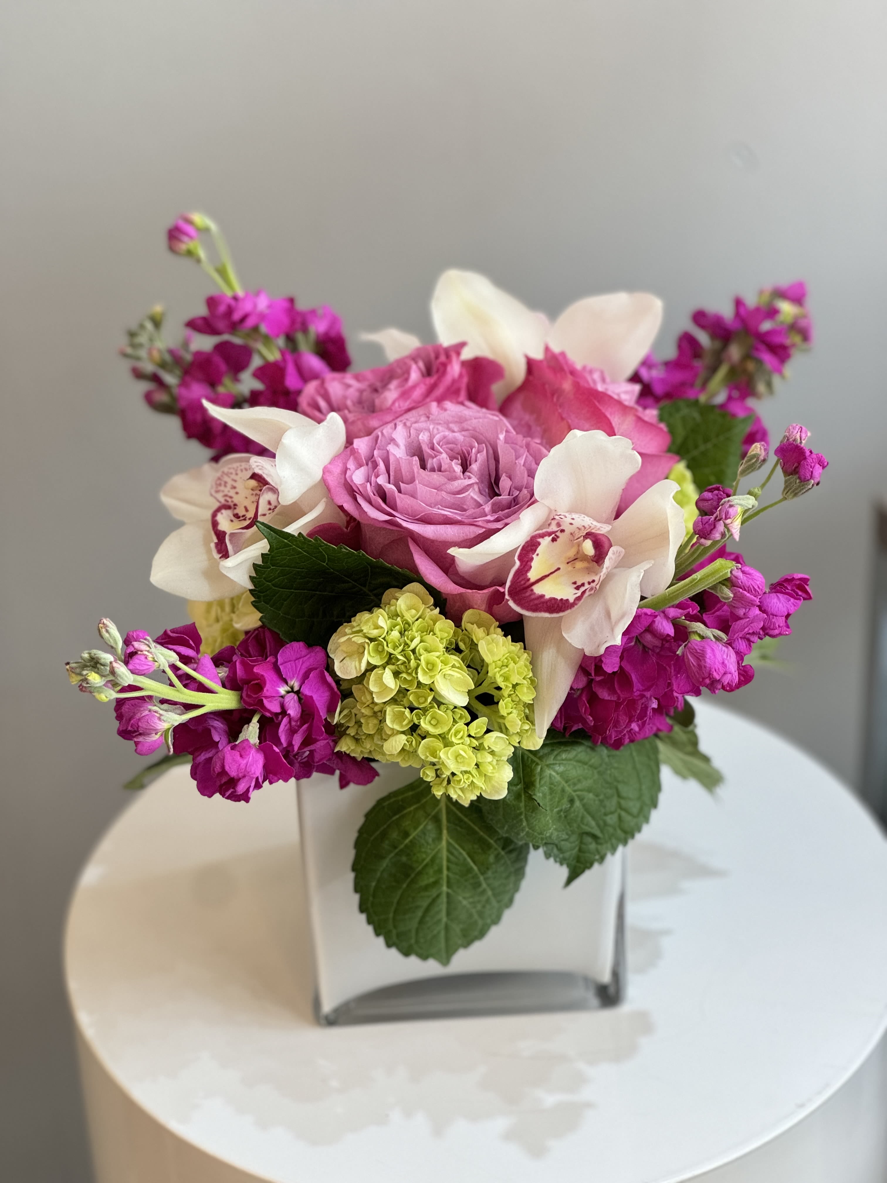 Pink and white floral arrangement in a square glass vase