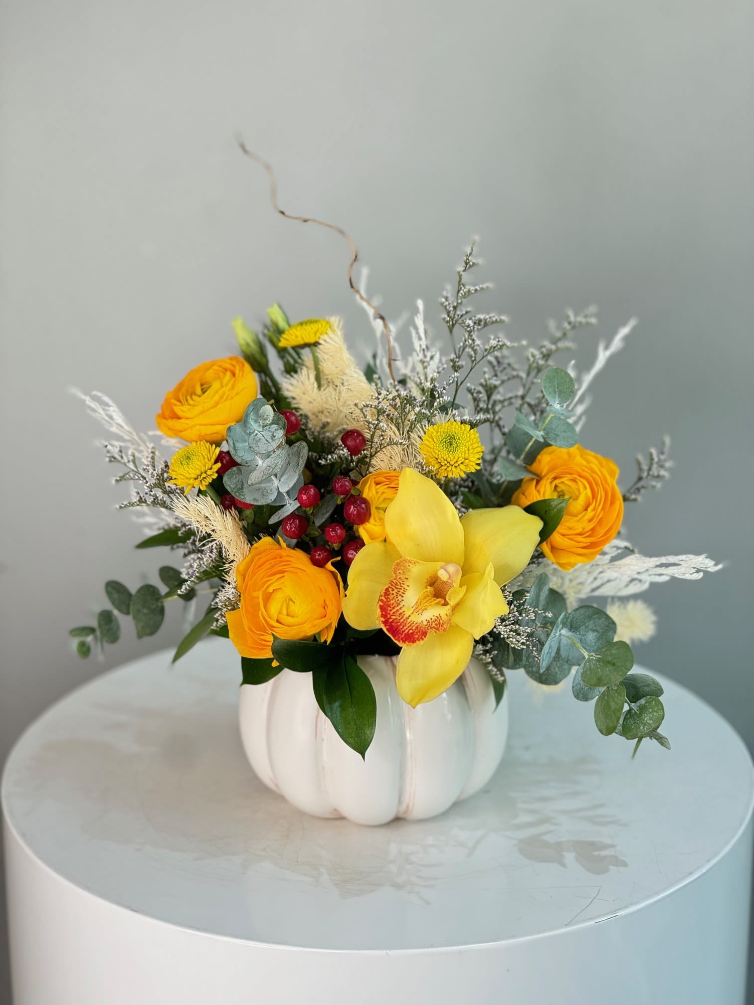 Ceramic Pumpkin With Fresh Flowers - small/white Fall colors ™ - Bright yellow roses, golden orchids, and cheerful berries spill from a charming white pumpkin vase, accented with silver eucalyptus and soft pampas. This festive design blends autumn warmth with elegant textures, making it perfect for seasonal celebrations or as a striking centerpiece.