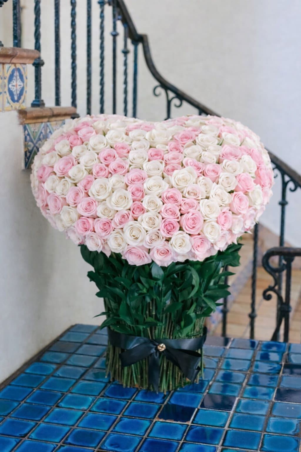 Large bouquet of pink and white roses tied with a black ribbon