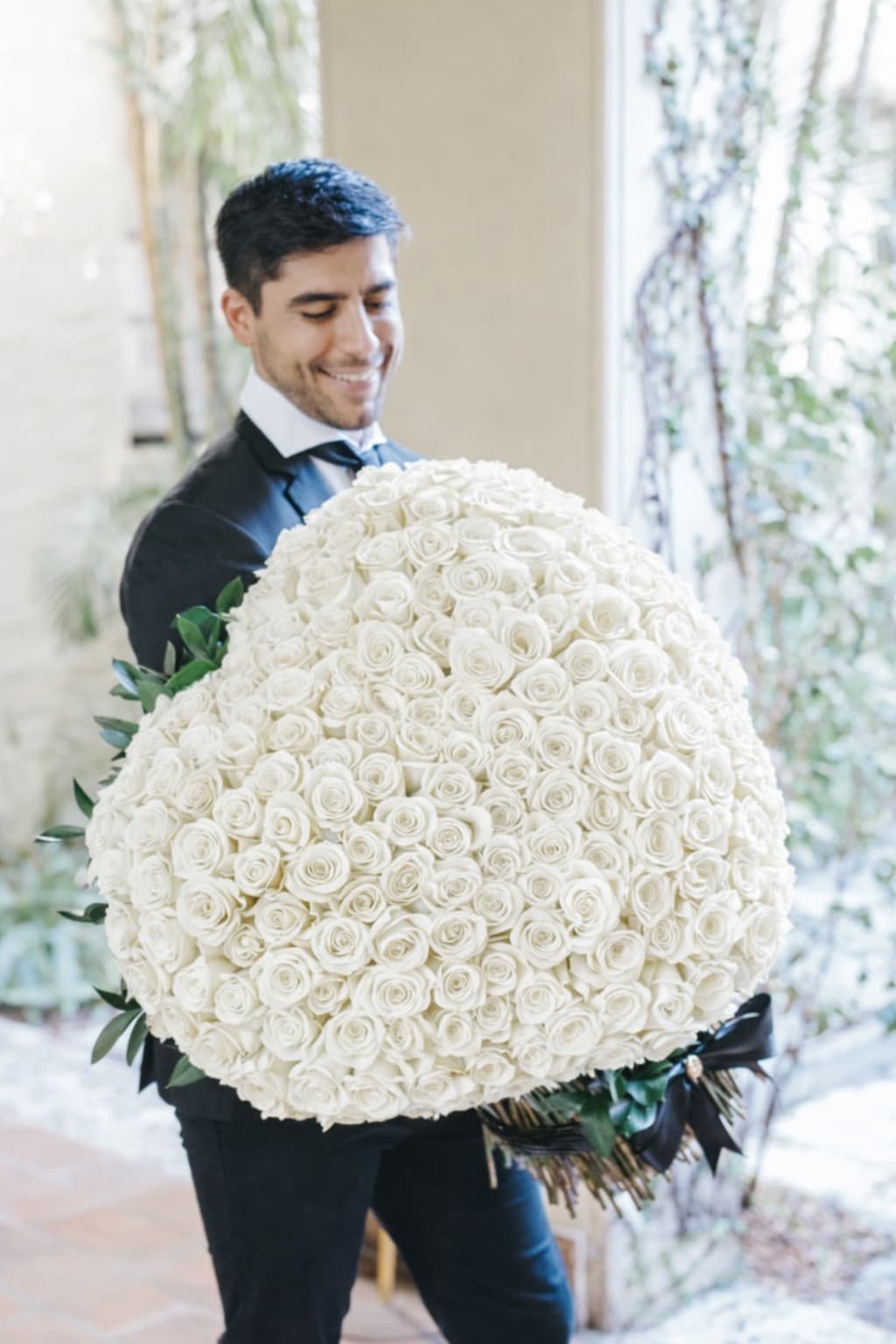 Man holding a large round bouquet of white roses