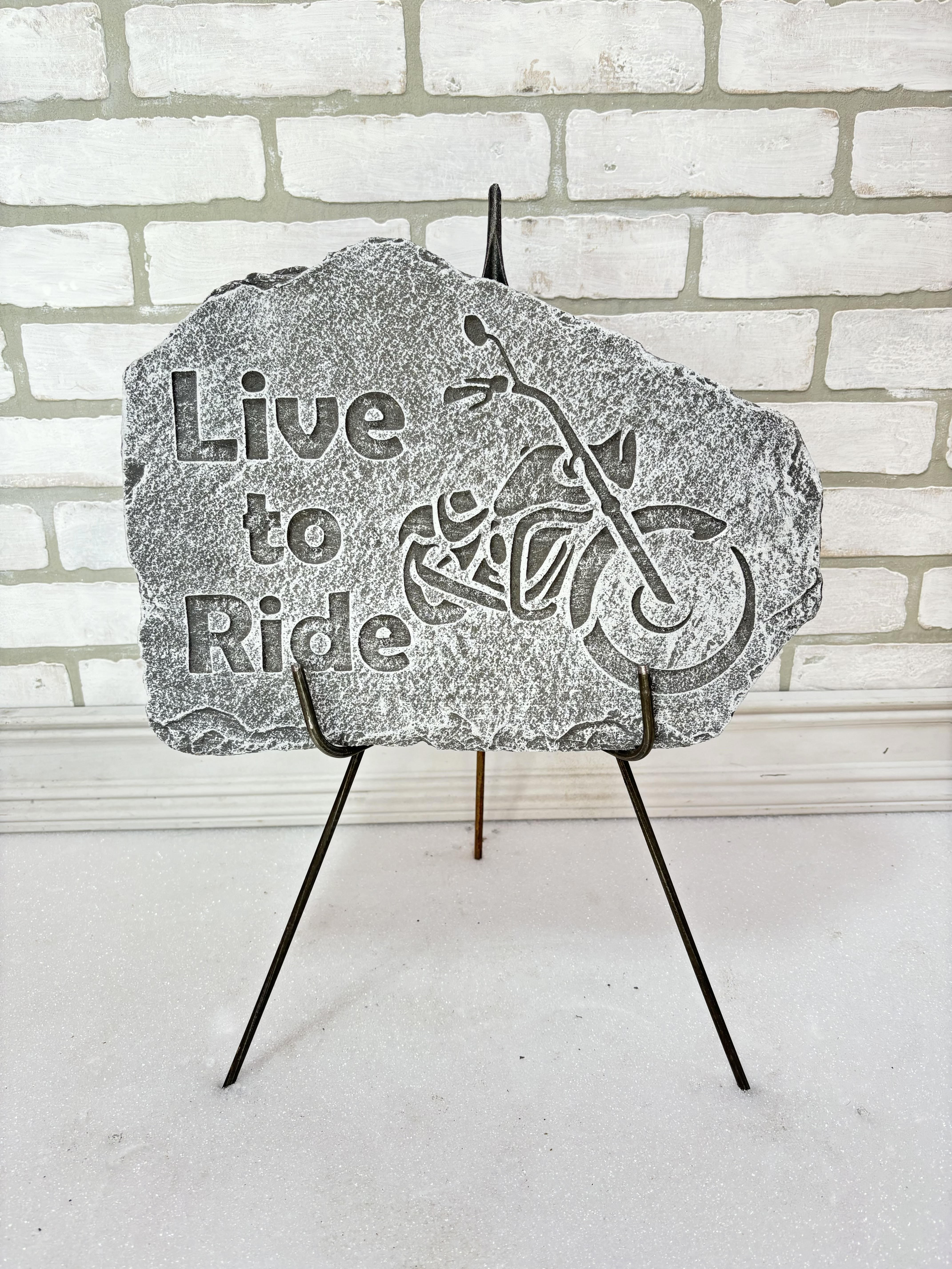 Stone memorial plaque reading "Live to Ride" on a metal stand