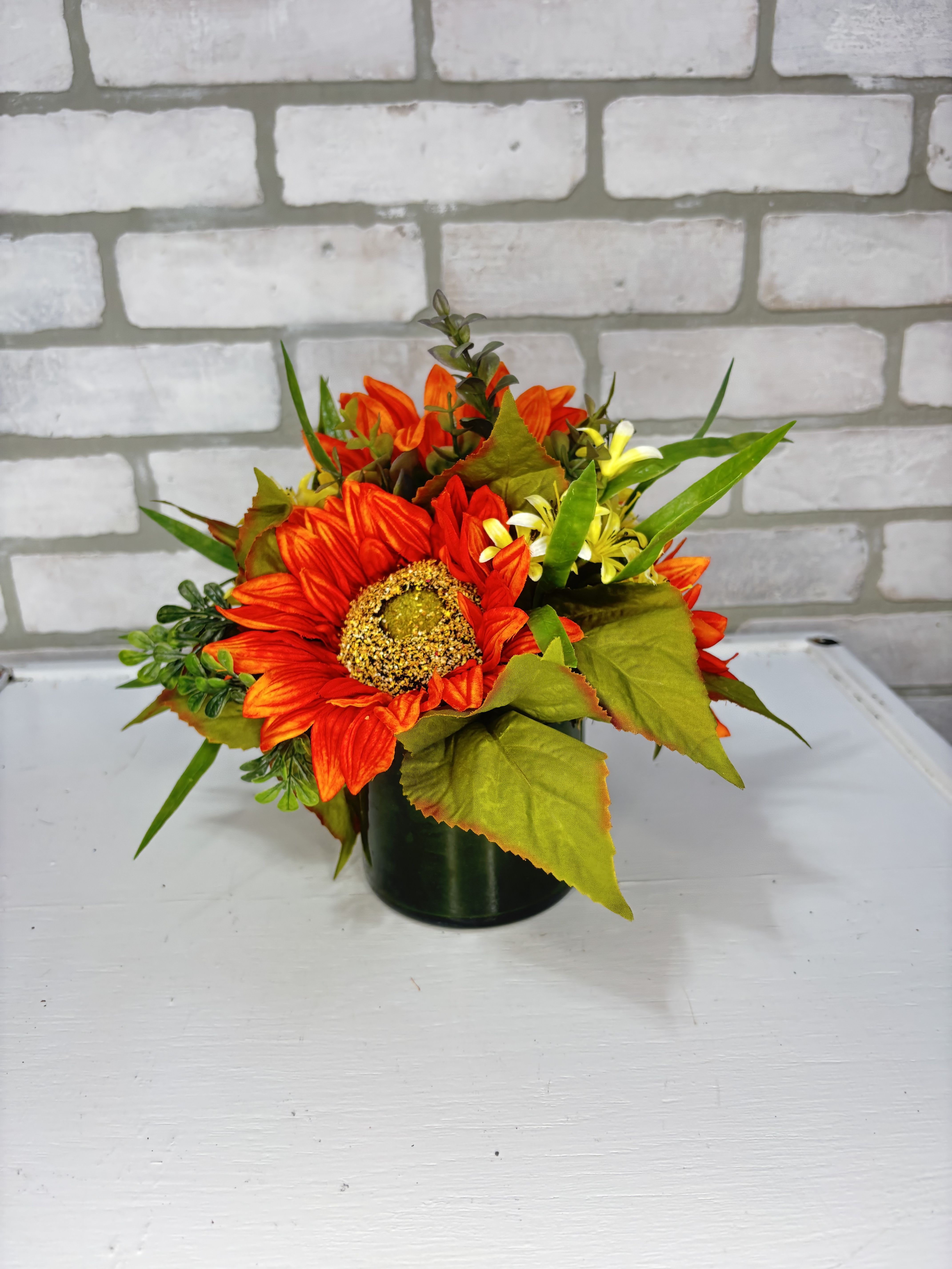 Orange sunflower arrangement in a dark vase
