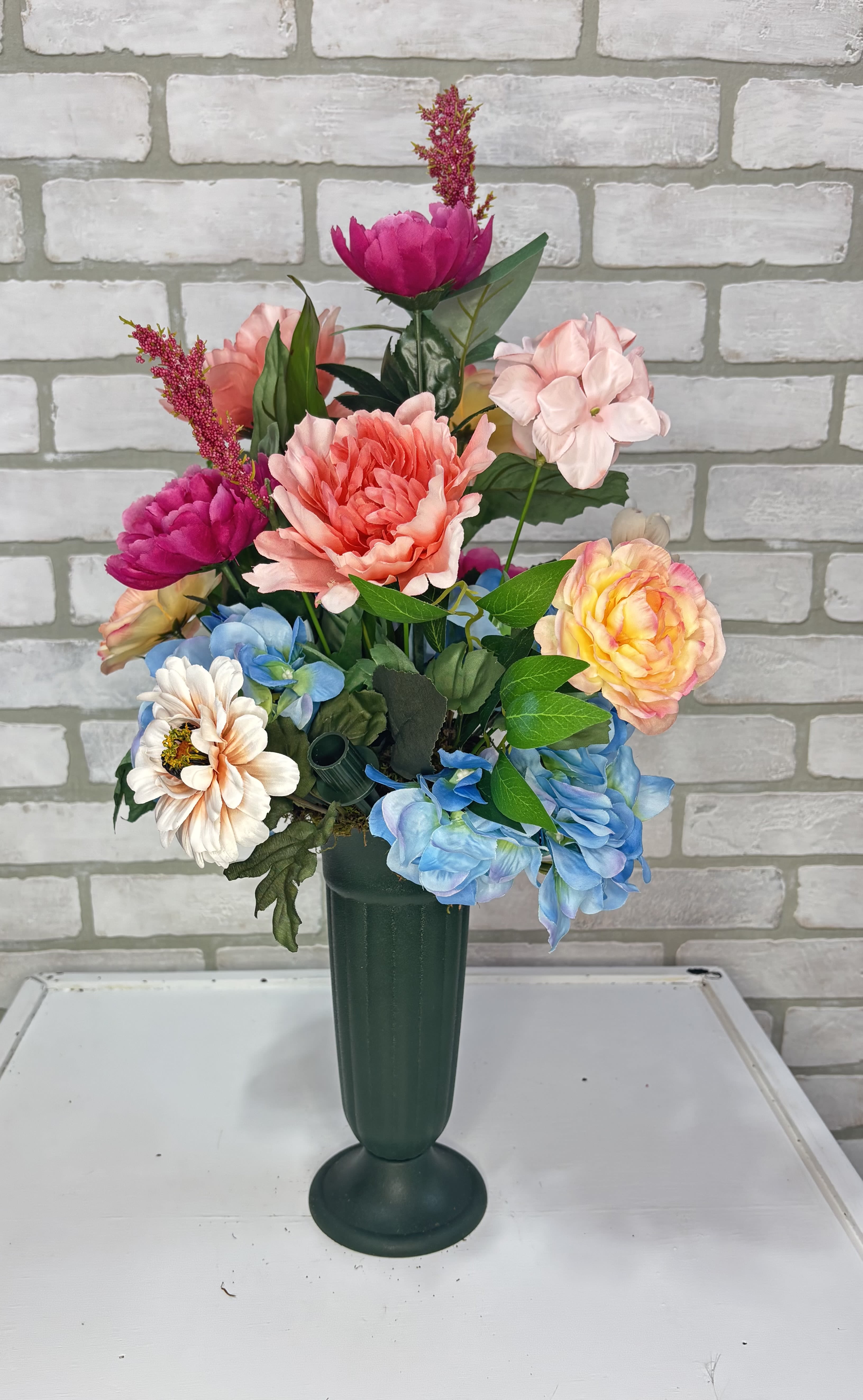 Colorful mixed flower arrangement in a tall green vase