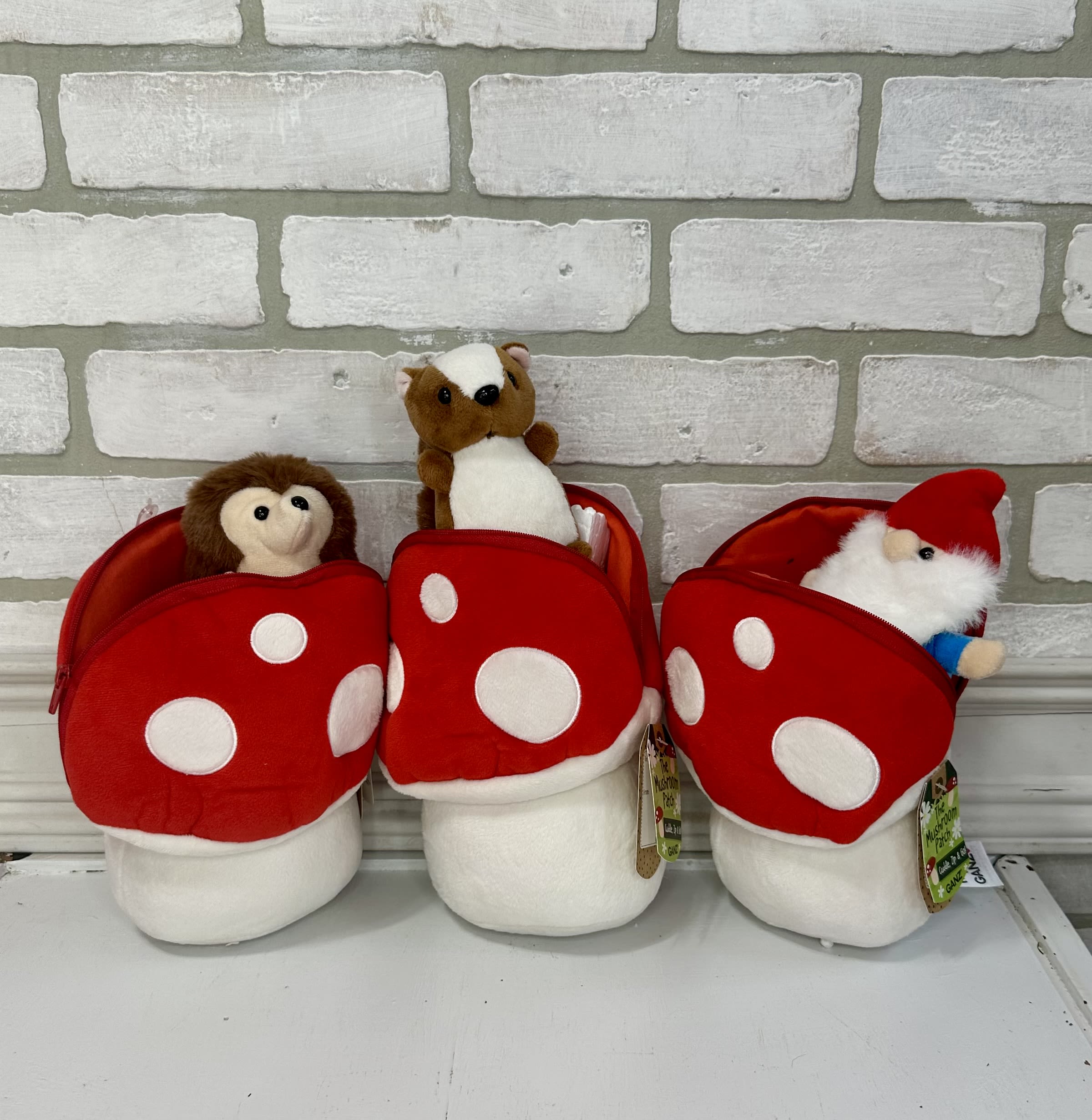Three plush holiday gnomes in red mushroom-shaped pouches