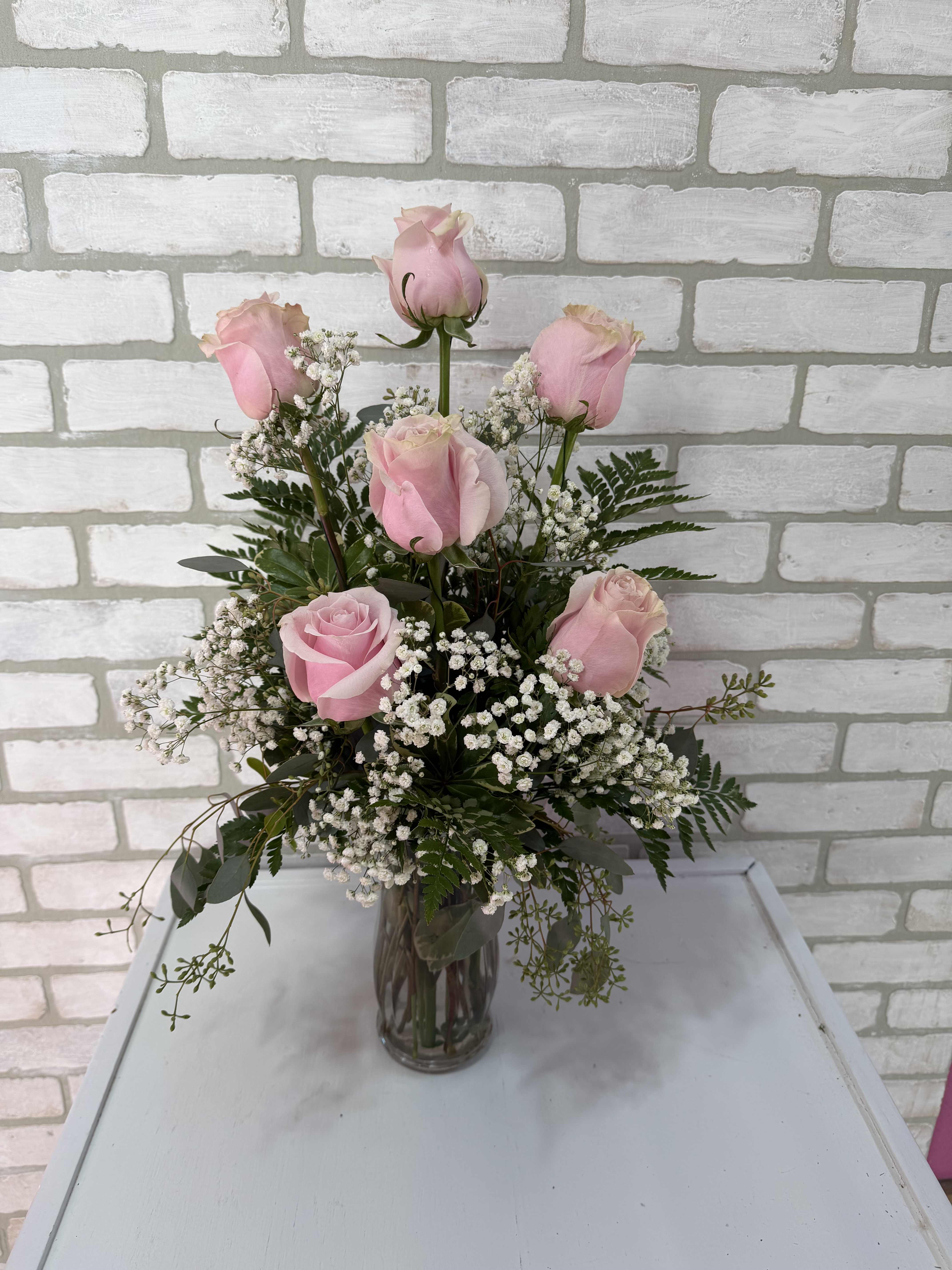 Pink roses arranged in a clear glass vase with white baby's breath