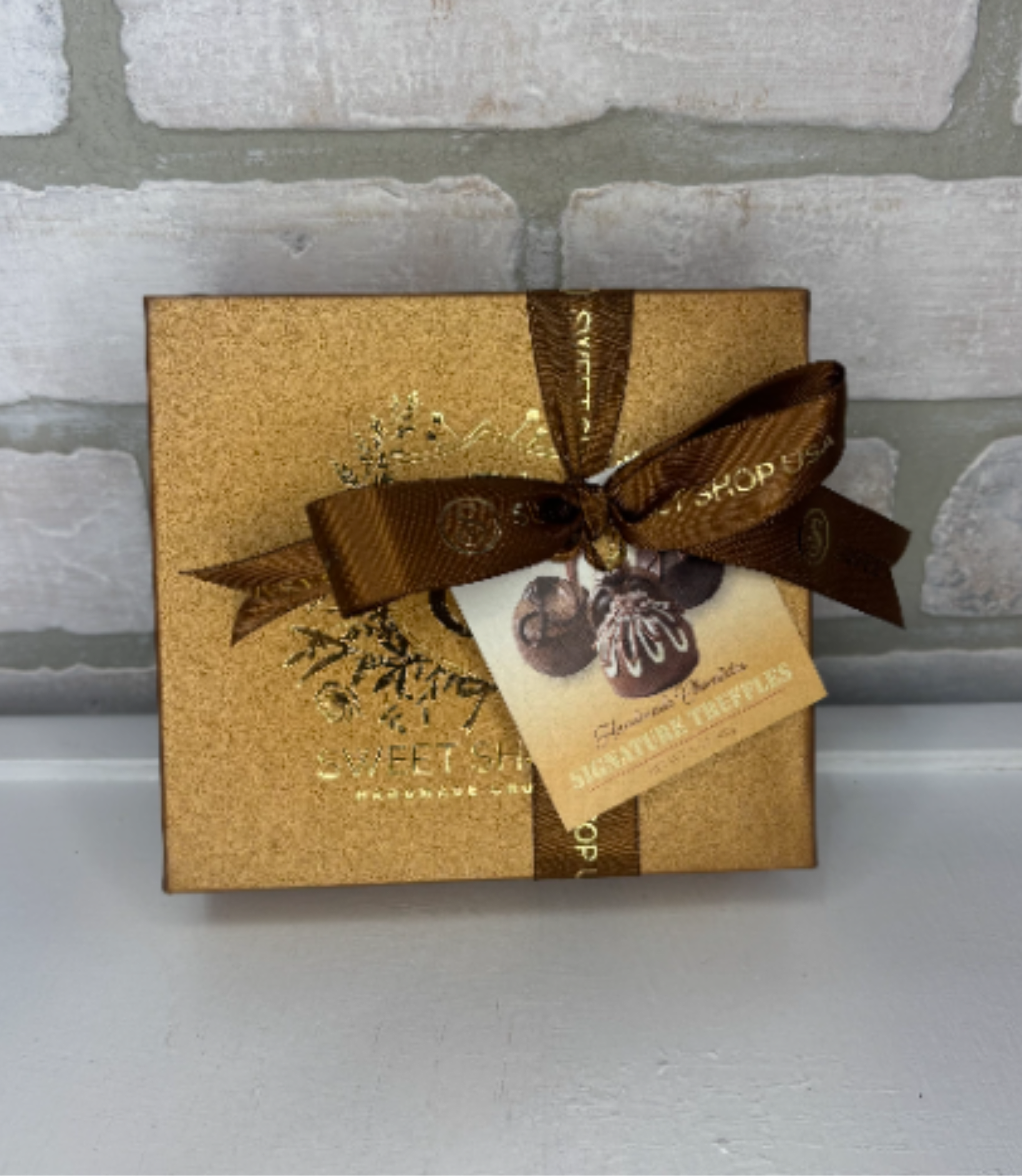 Gold chocolate gift box with brown ribbon and truffle tag