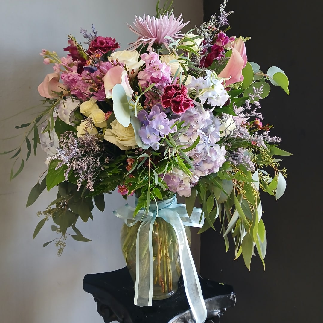 Large mixed bouquet in a glass vase with a pale ribbon
