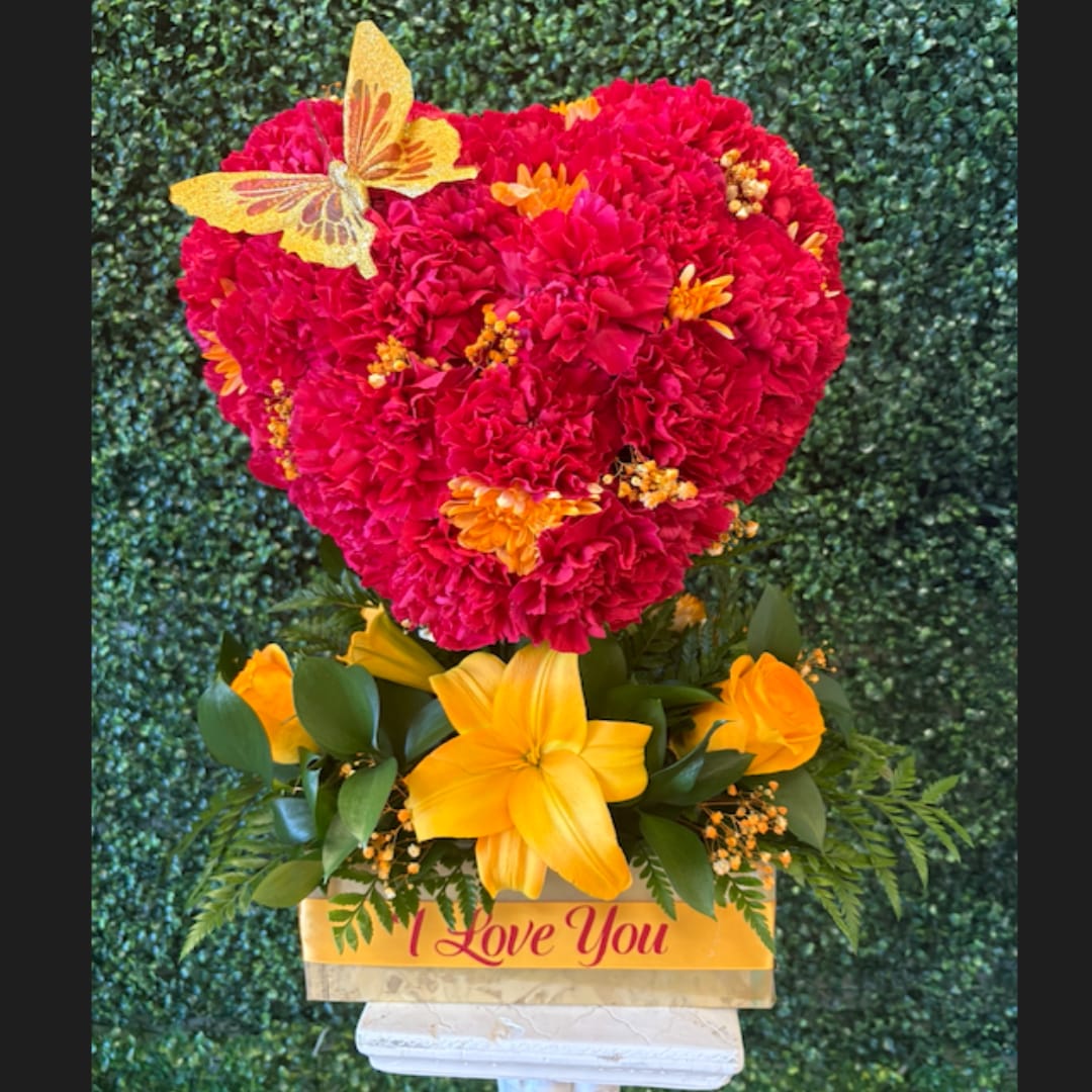 Heart-shaped red carnation arrangement with yellow flowers and a butterfly topper