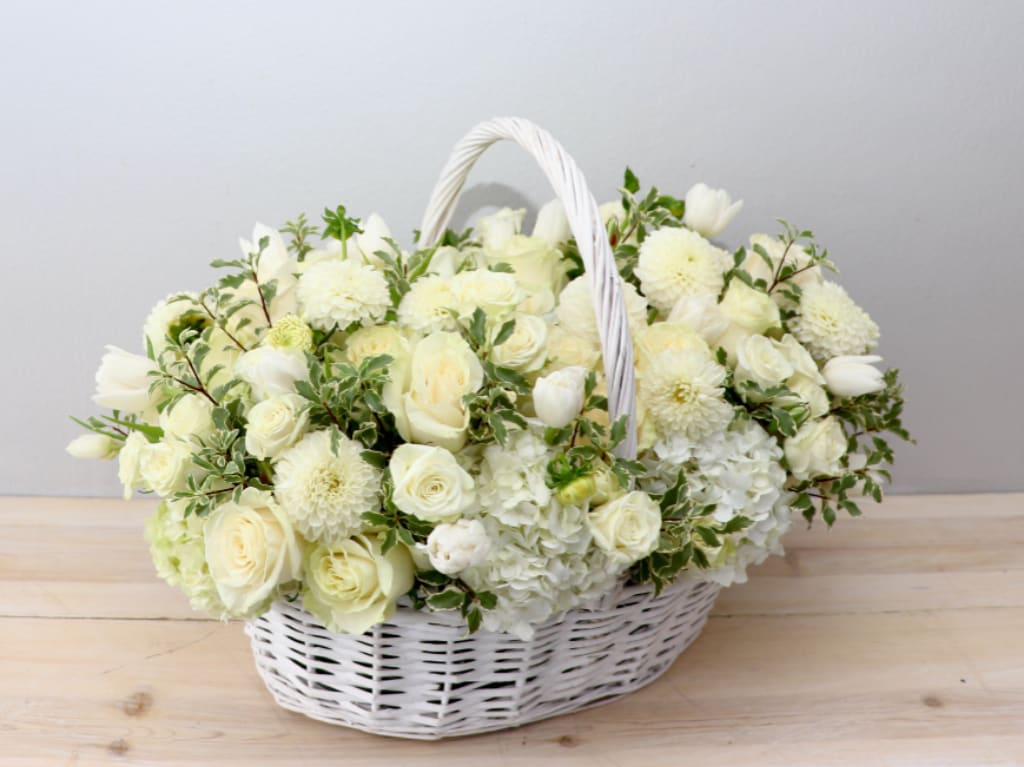 White flower basket with roses, tulips, and mums in a wicker basket