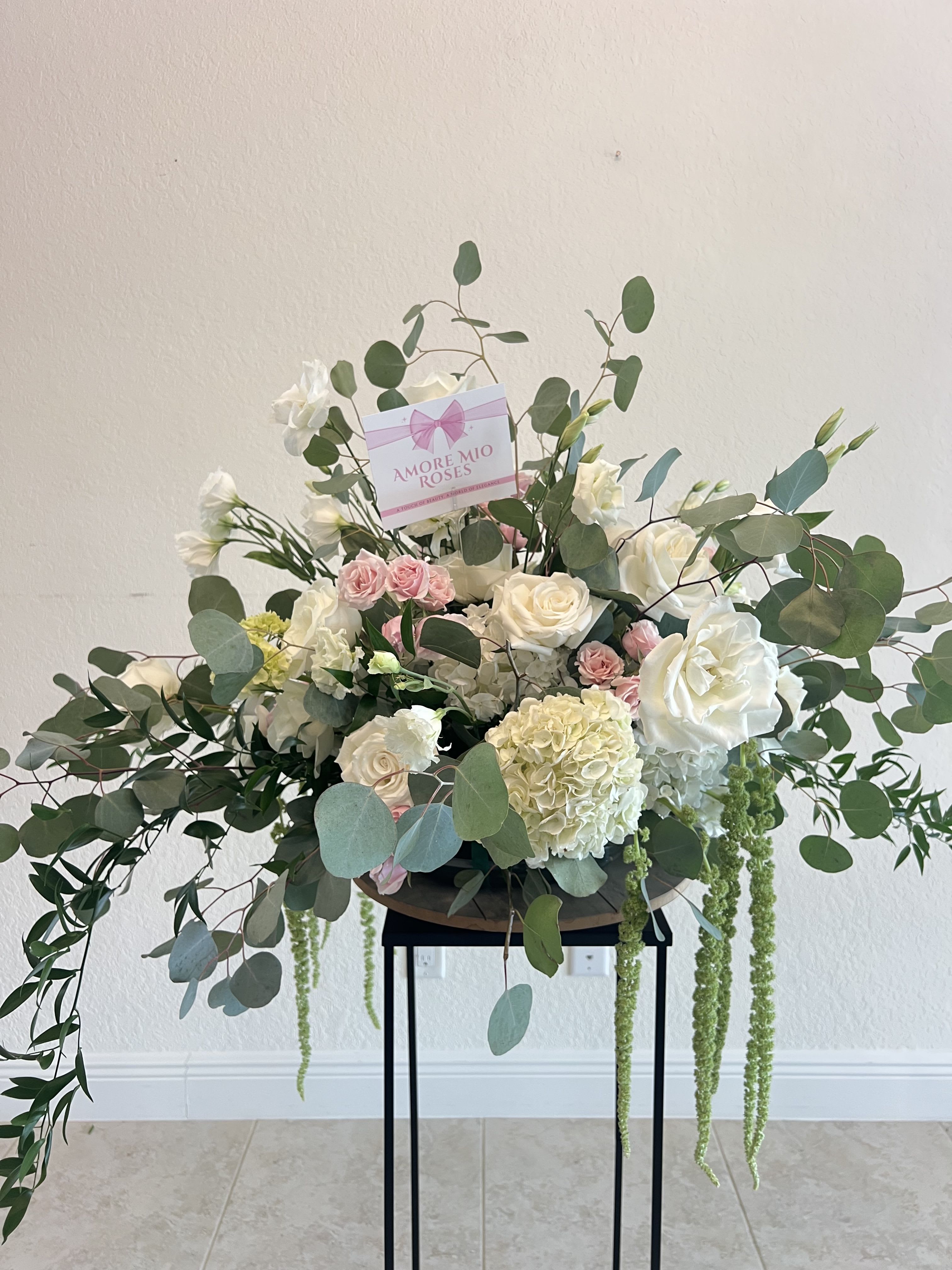 Large white and pink rose arrangement with eucalyptus and trailing greenery