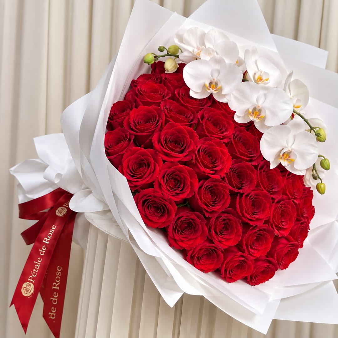Bouquet of red roses with white orchids wrapped in white paper