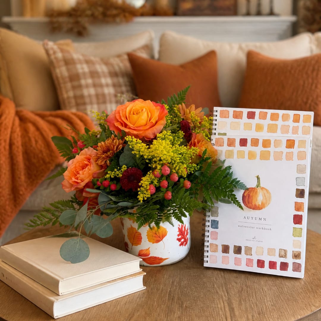 Orange rose bouquet in a painted white vase with autumn decor