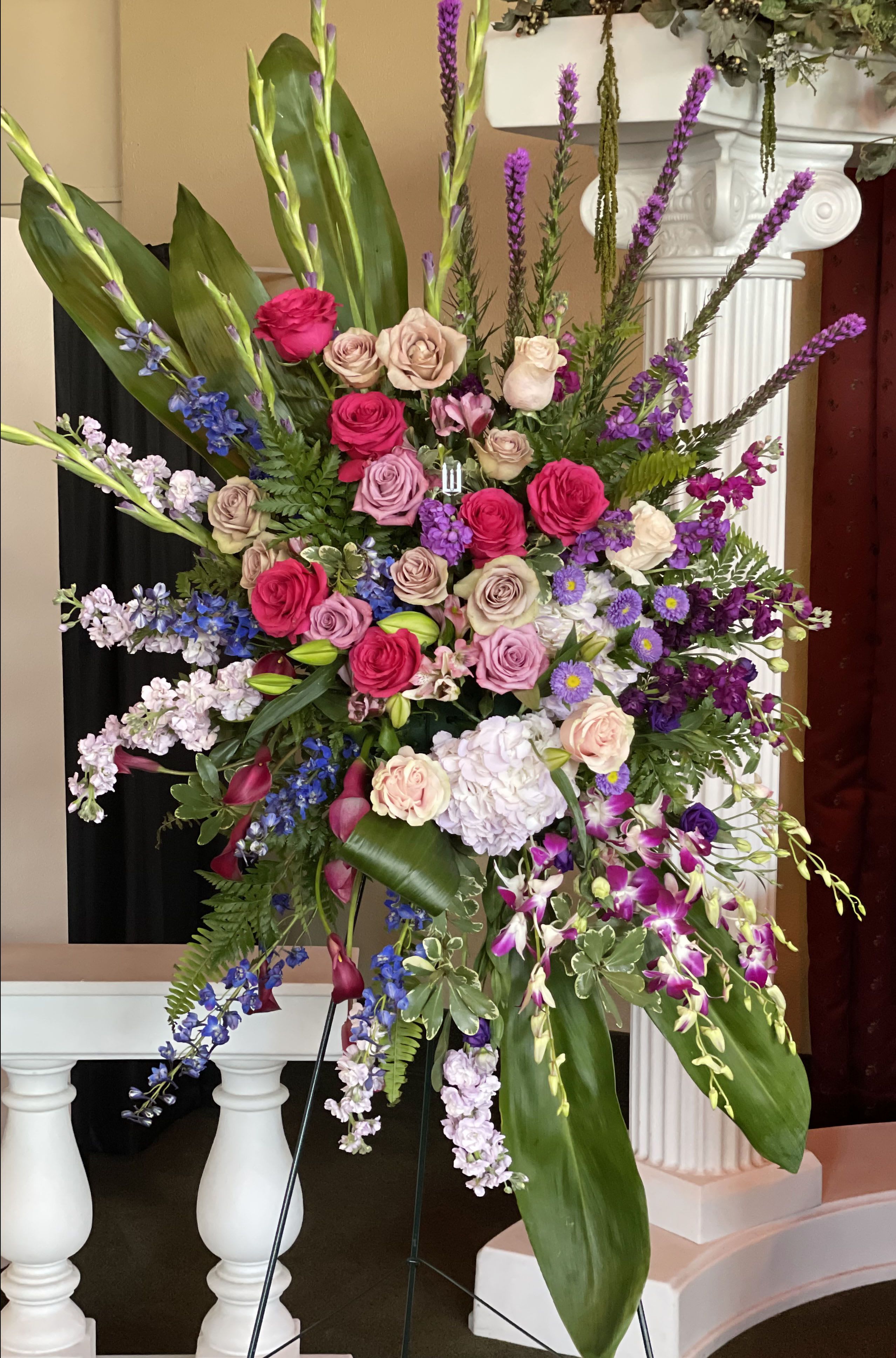 Large standing floral spray with pink, purple, and white blooms