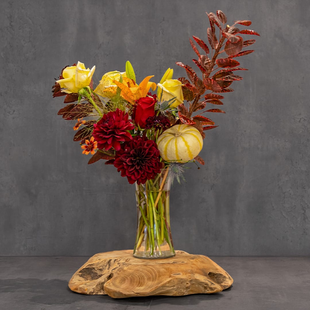 Autumn bouquet of red and yellow flowers in a clear glass vase