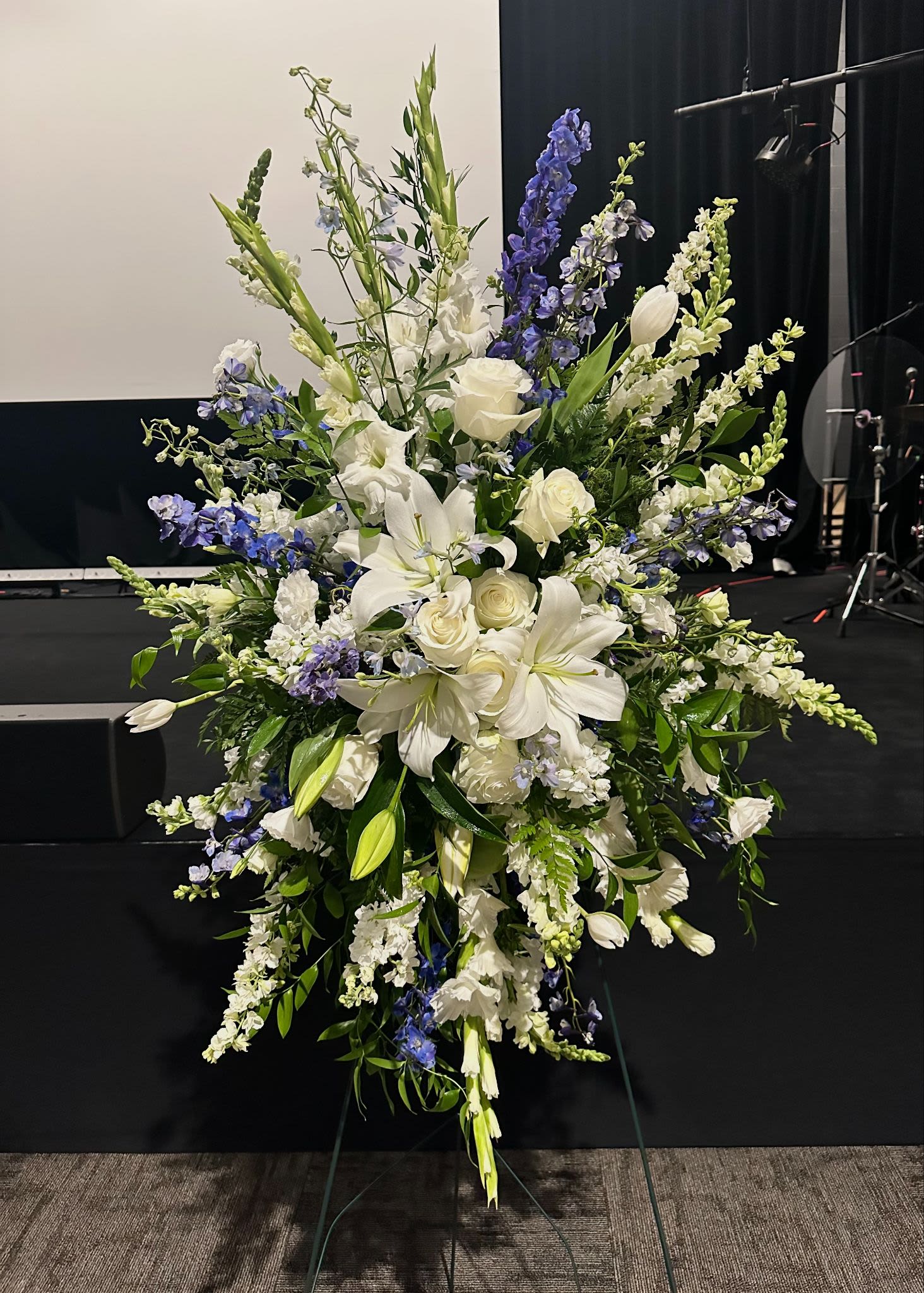 Tall white and blue floral standing spray on an easel