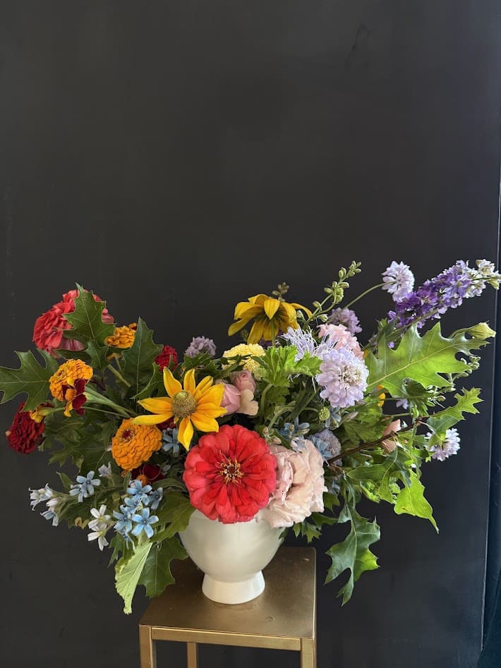 Colorful mixed bouquet in a white vase with zinnias and daisies