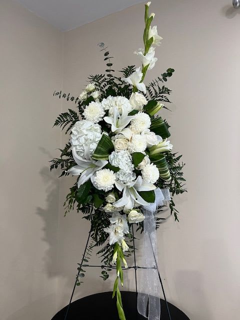 Tall white floral standing spray with lilies and mums on an easel