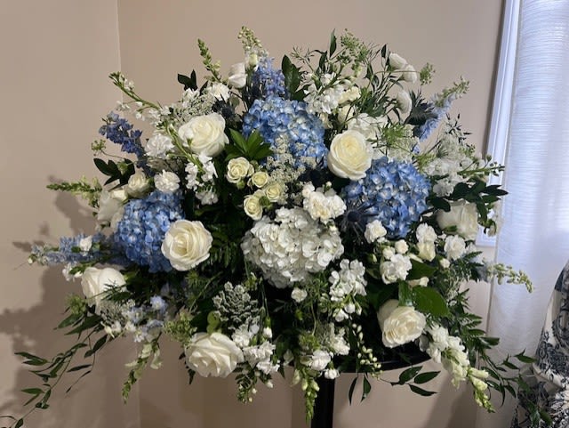 Large white and blue floral arrangement on a stand